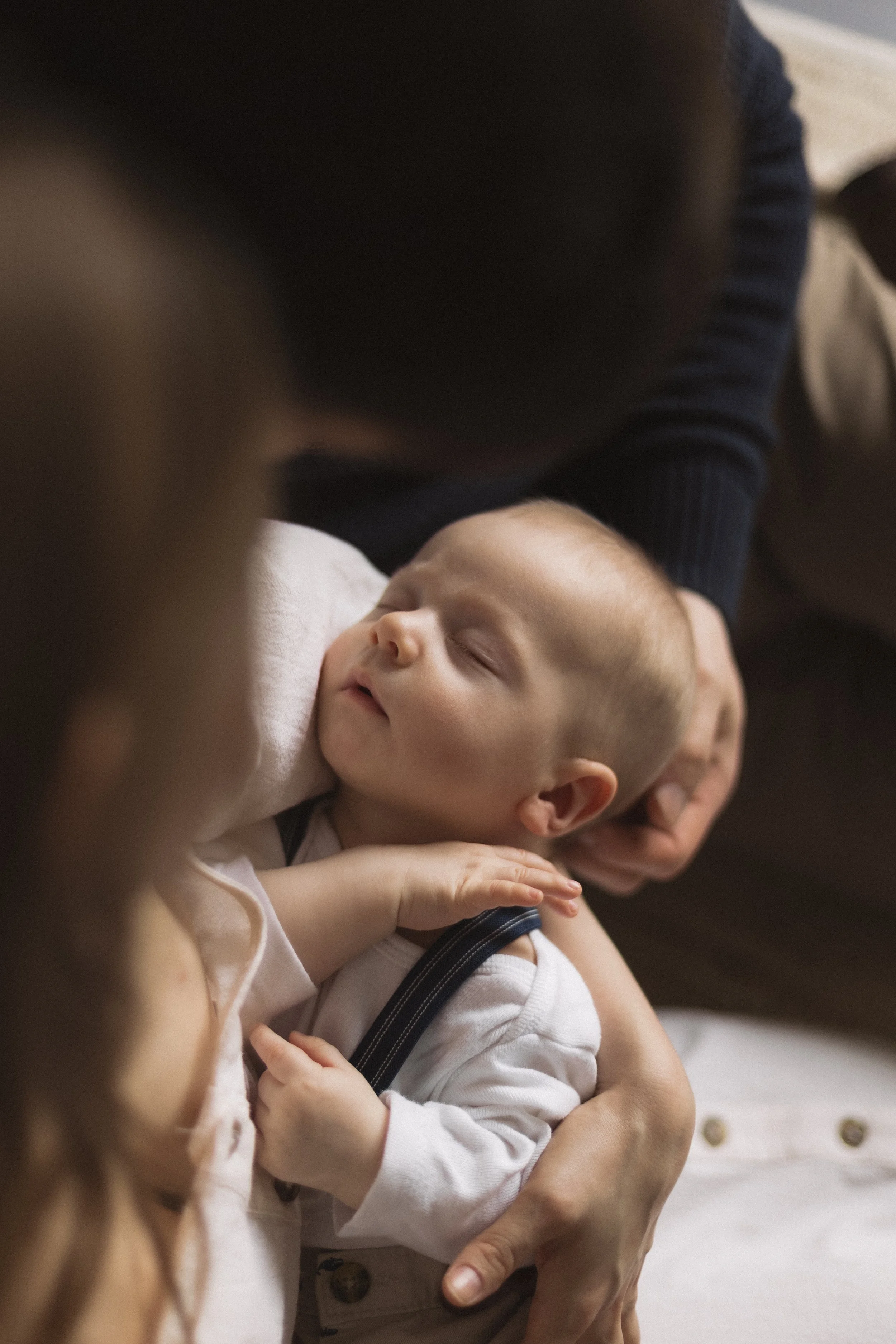 Ein schlafender Baby, das von Erwachsenen gehalten wird.