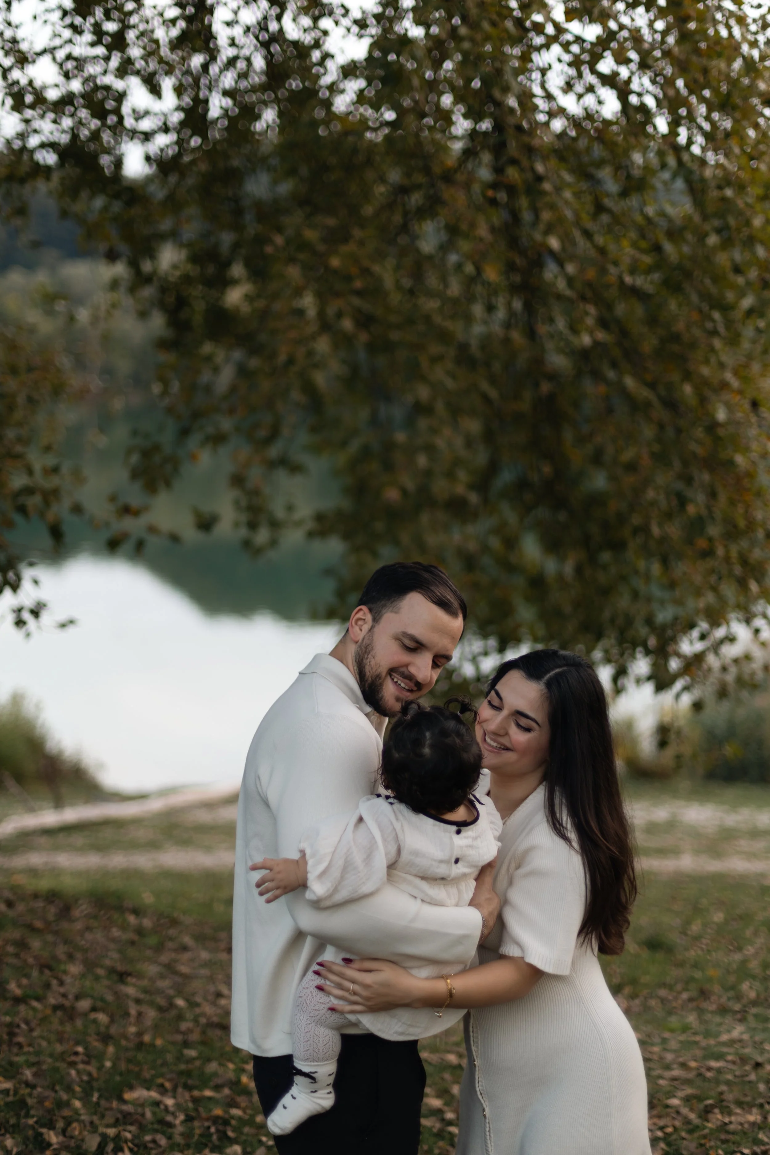 Vater hebt sein Kind lachend in die Luft auf einer Wiese in Landshut, voller Lebensfreude. Father lifting his child into the air on a meadow in Landshut, full of joy.