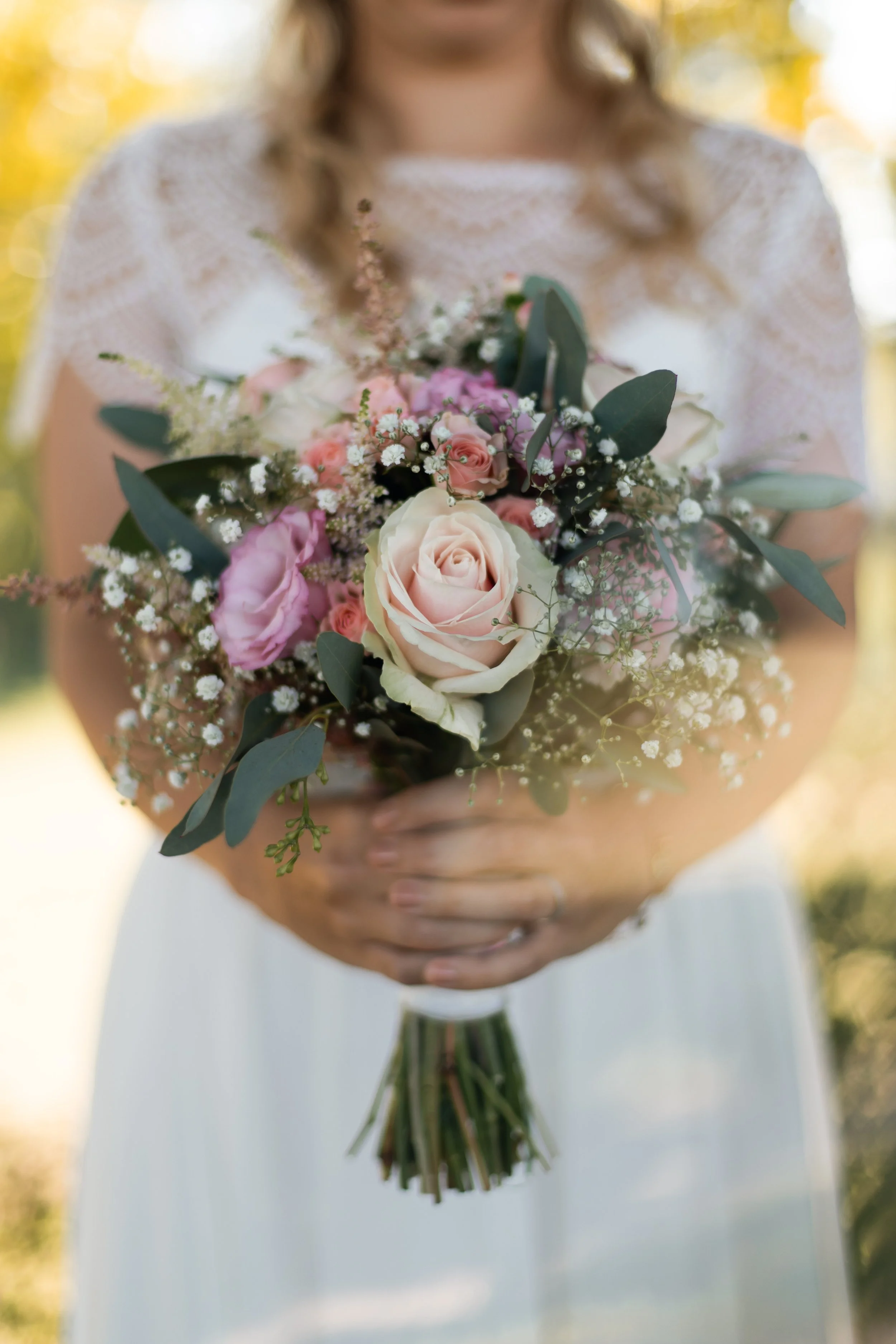 Braut hält ihren Blumenstrauß vor dem Schloss in Bayern, stilvolle und romantische Hochzeitsfotografie. Bride holding her bouquet in front of a castle in Bavaria, elegant and romantic wedding photography.