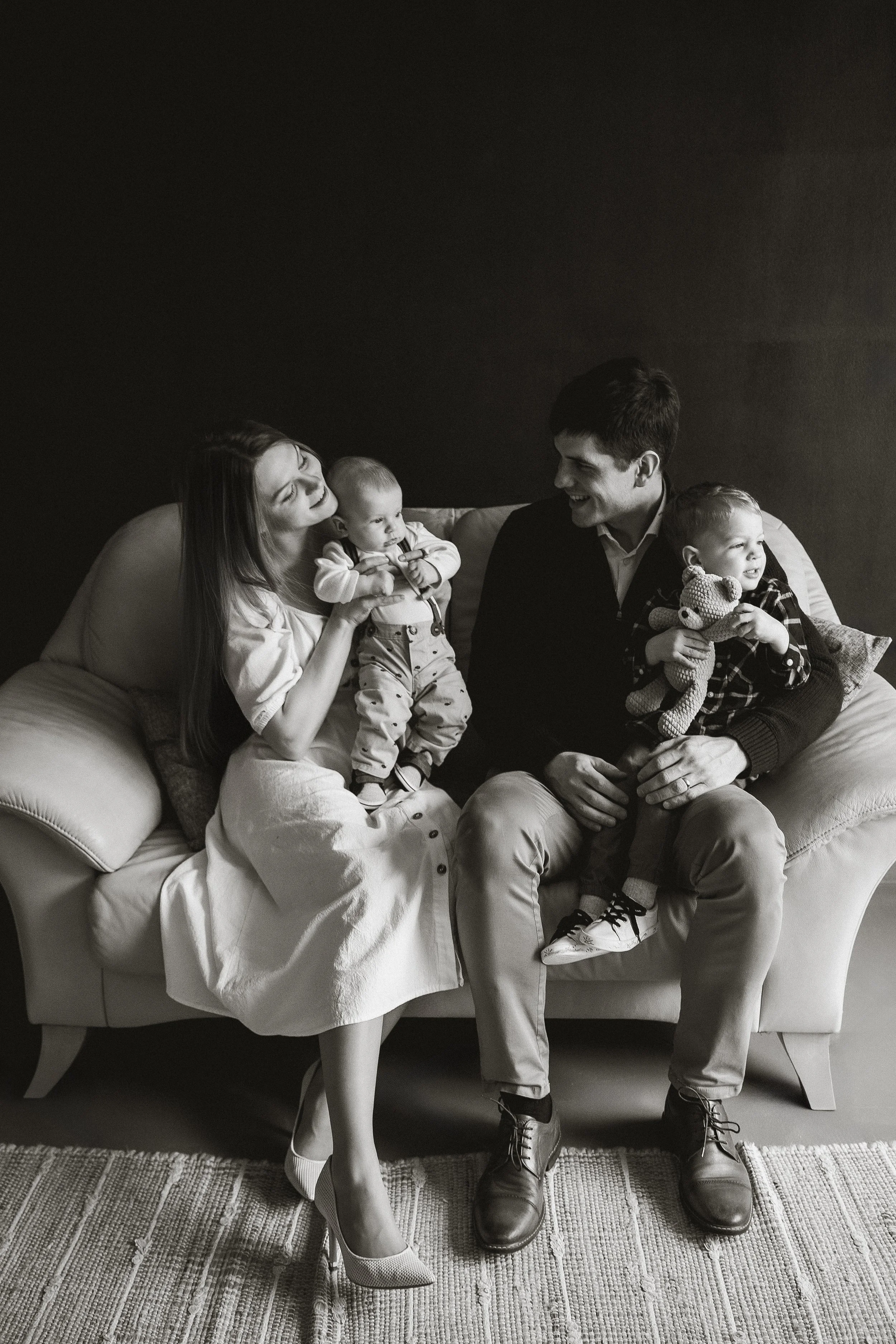 Familie mit zwei Kindern sitzt auf einem Sofa und lacht