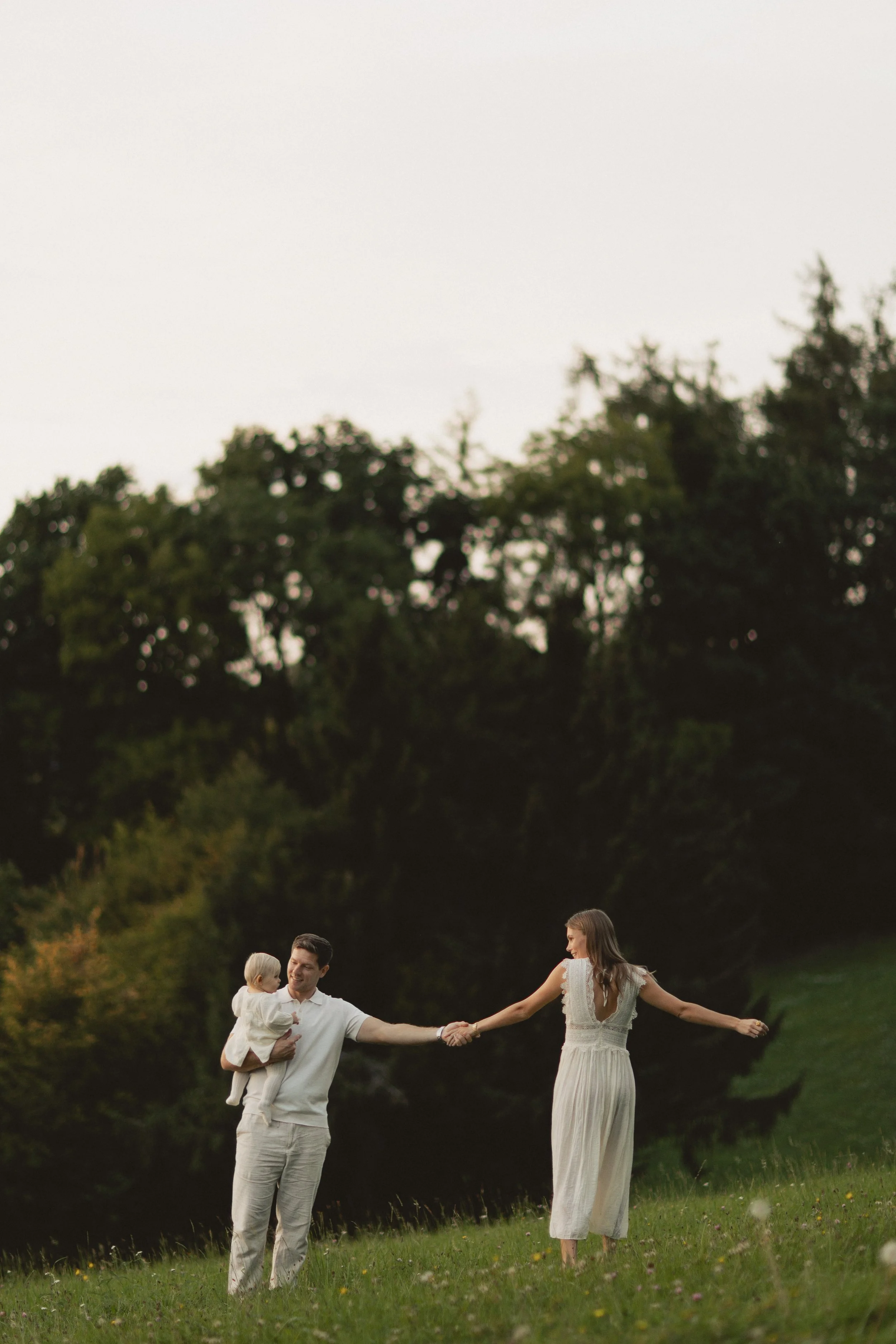 Eltern umarmen ihr Kind bei einem natürlichen Familienfotoshooting in Bayern, emotionale und bleibende Erinnerungen. Parents embracing their child during a natural family photo session in Bavaria, creating emotional and lasting memories.