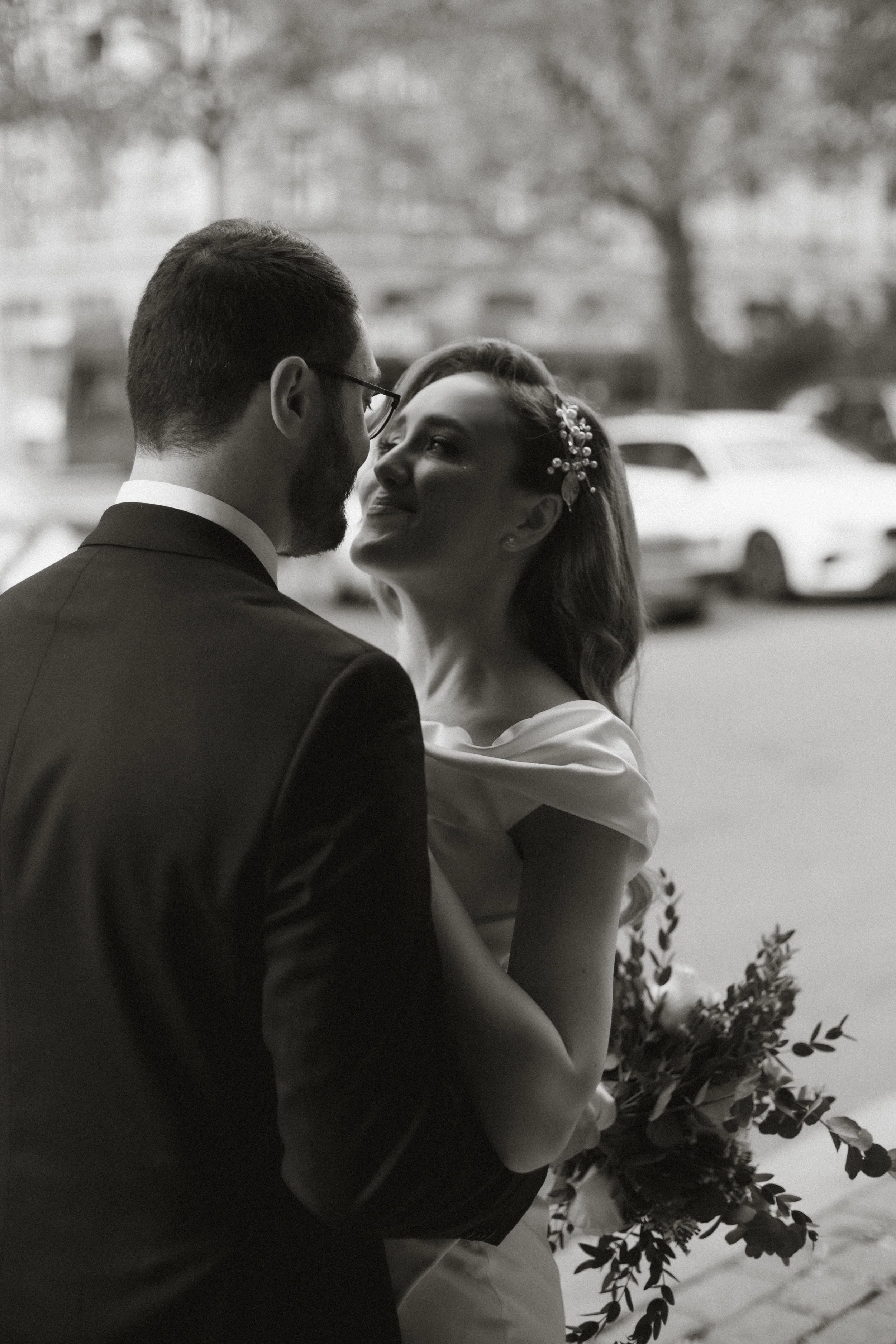 Brautpaar bei Hochzeit, Frau mit Blumen im Haar, Mann in Anzug, im Freien, im Hintergrund Autos, schwarz-weiß
