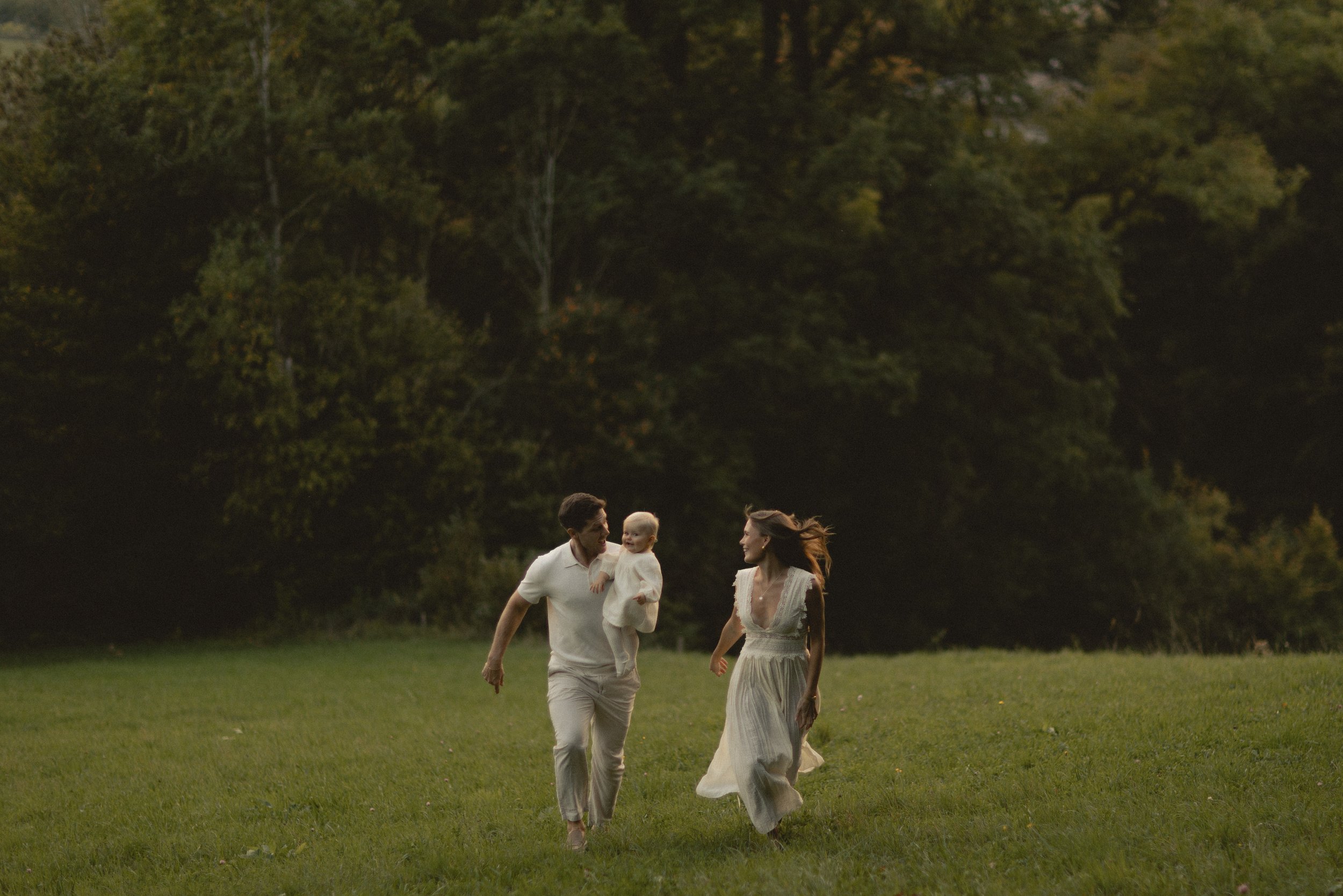 Familie mit Kind spaziert über eine Wiese in Bayern, natürliche und authentische Familienfotografie. Family with child walking across a meadow in Bavaria, natural and authentic family photography.