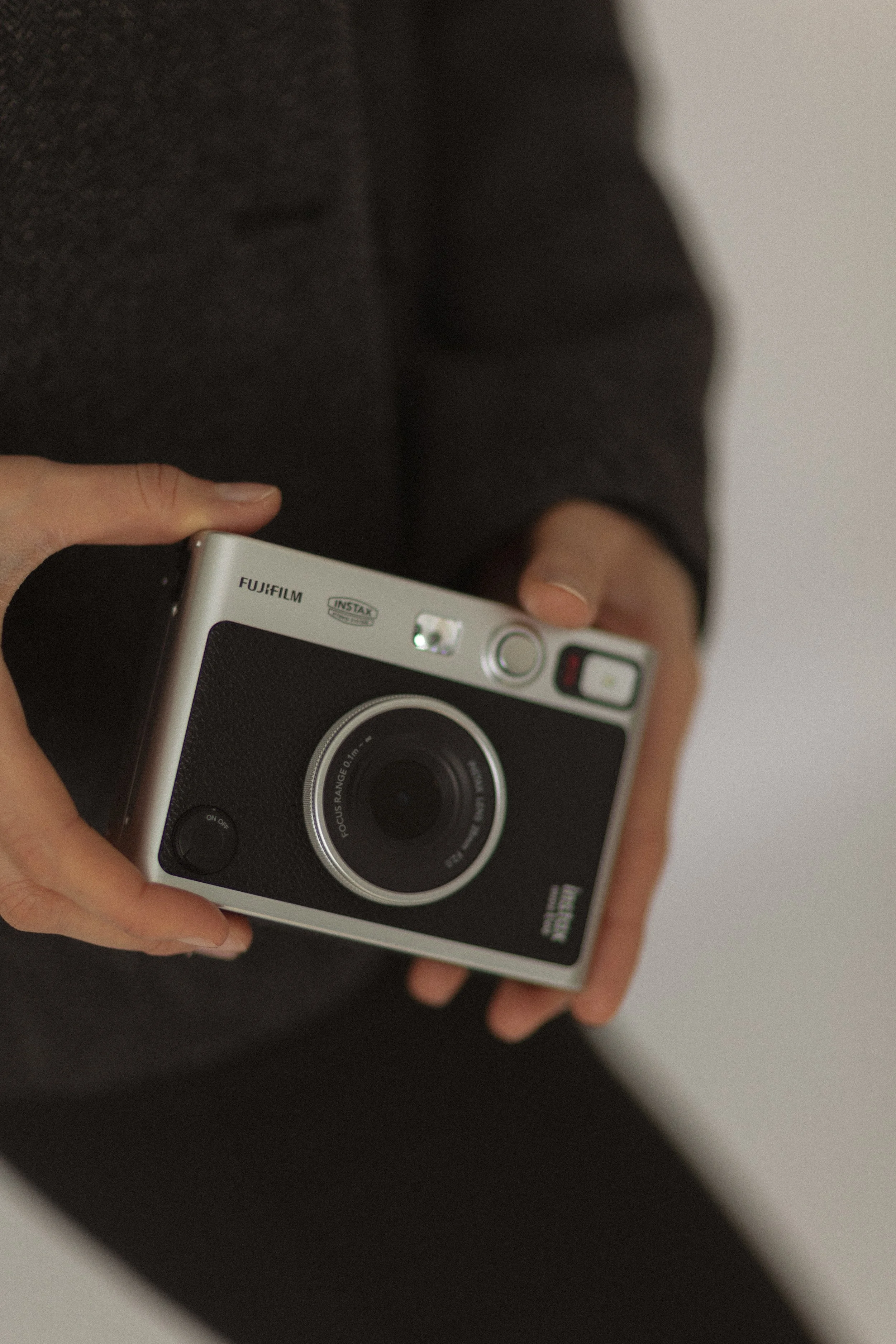 Person hält eine kleine, schwarze Kamera mit Silvergehäuse.