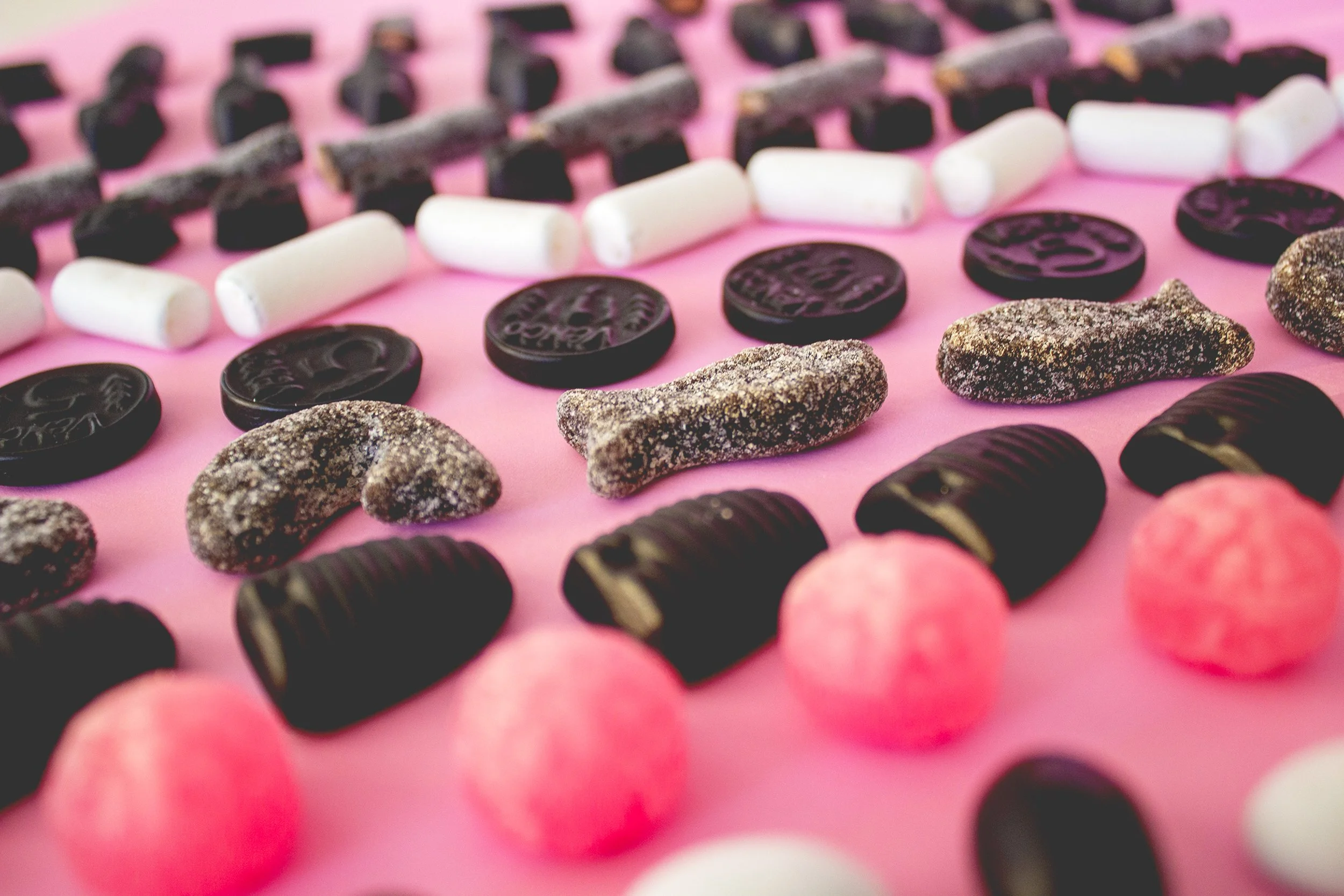 Dutch black liquorice pops against a pink backdrop