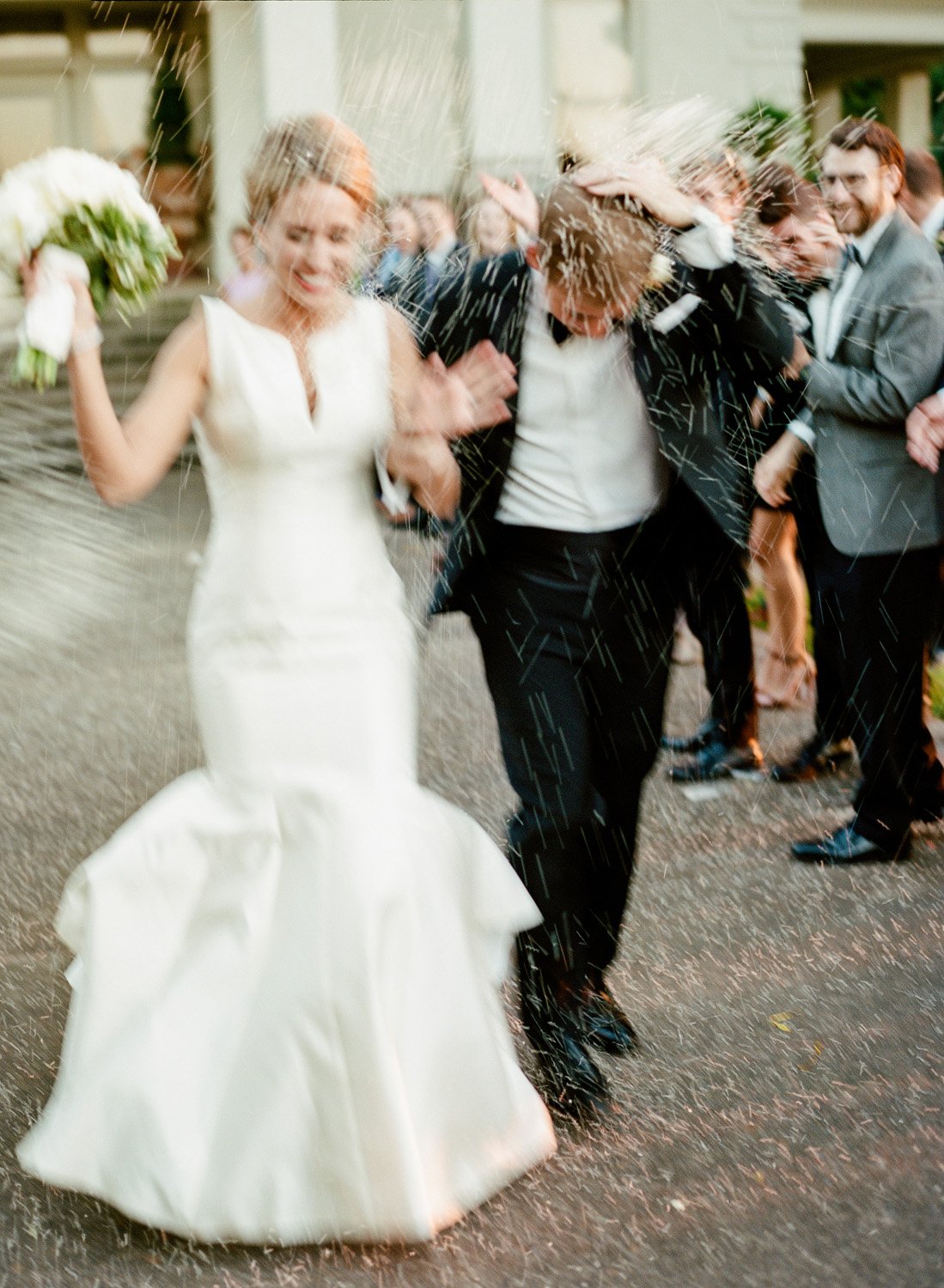 Bride and groom recessional with rice throwing by luxury wedding photographer Amanda Watson