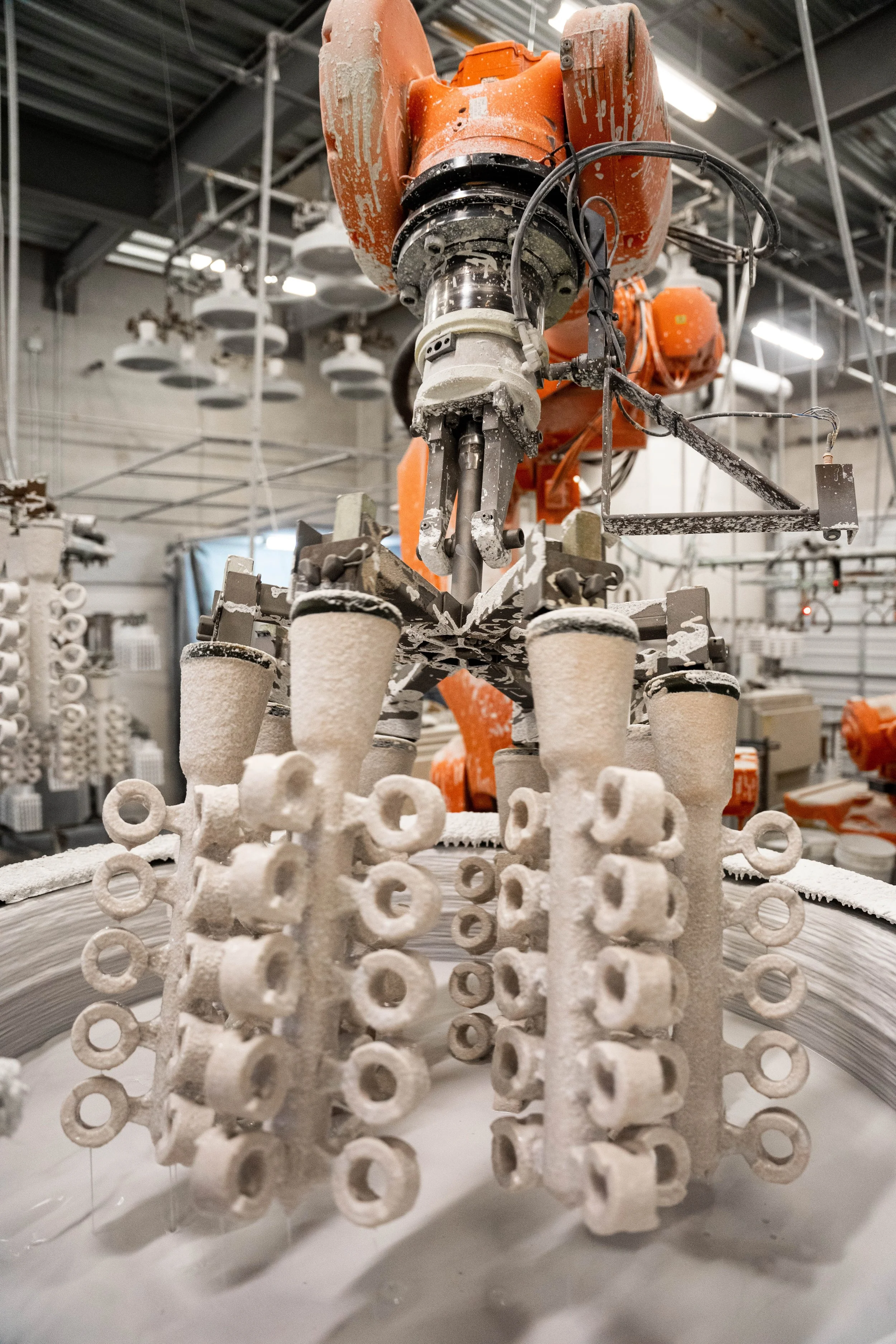 Several clusters of parts being dipped in a ceramic slurry at IPC Foundry Group.