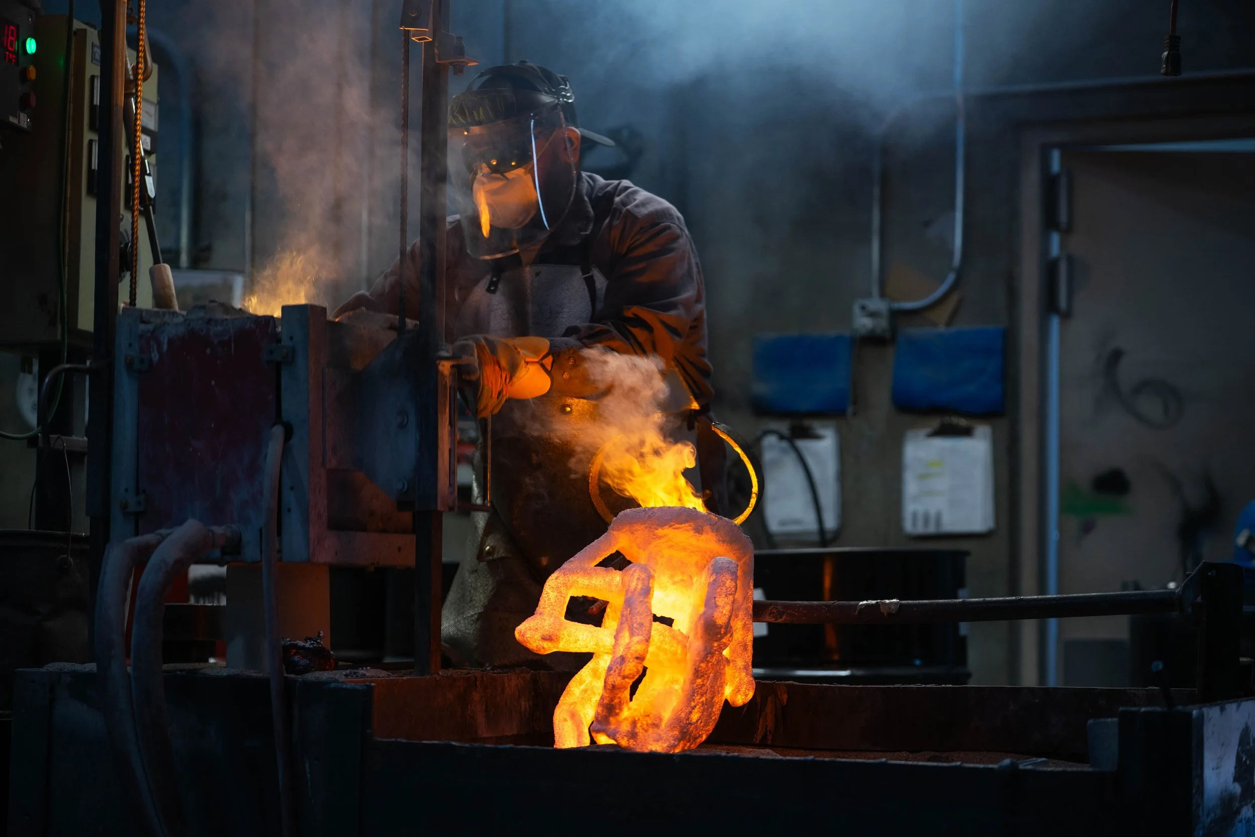 A foundry worker checks a crucible just after pouring an investment casting