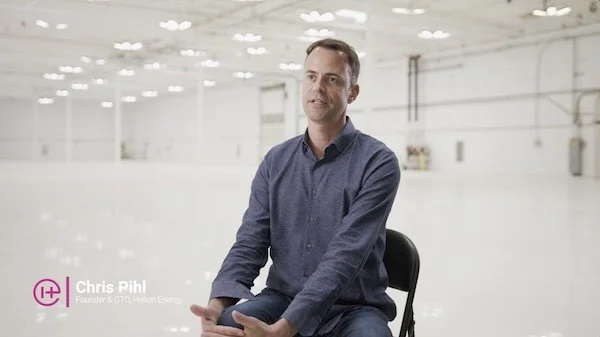 A man sitting on a black chair in an ice rink, wearing a blue button-up shirt. Text overlay reads: 'Chris Pihl, Founder & CTO of Helium Energy.'