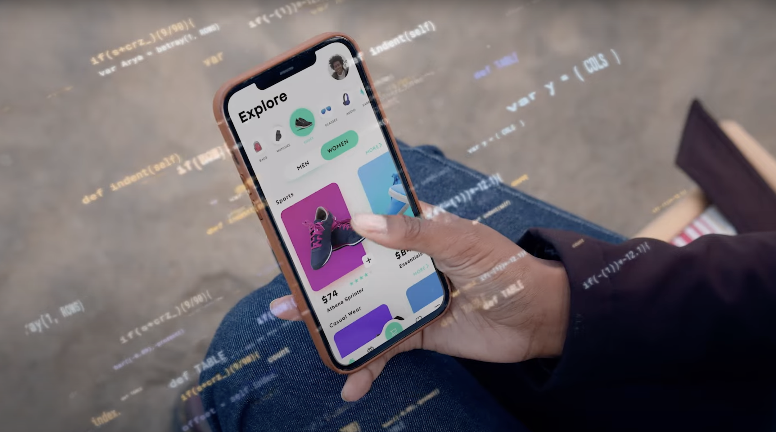 Hand holding a smartphone displaying a shopping app with sneaker options, overlaid with translucent code snippets.