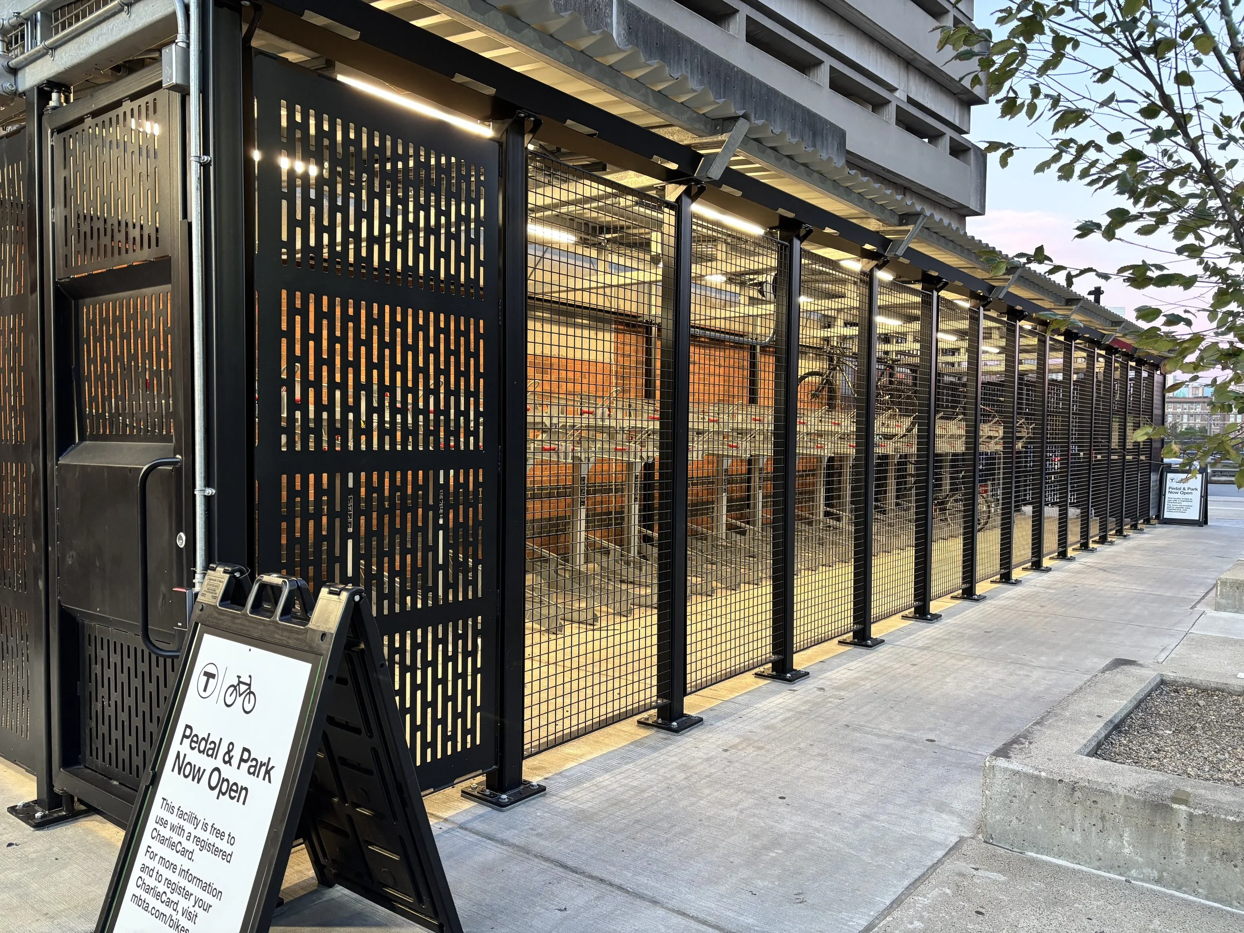Image of new bike cage with the "Now Open" sign in front