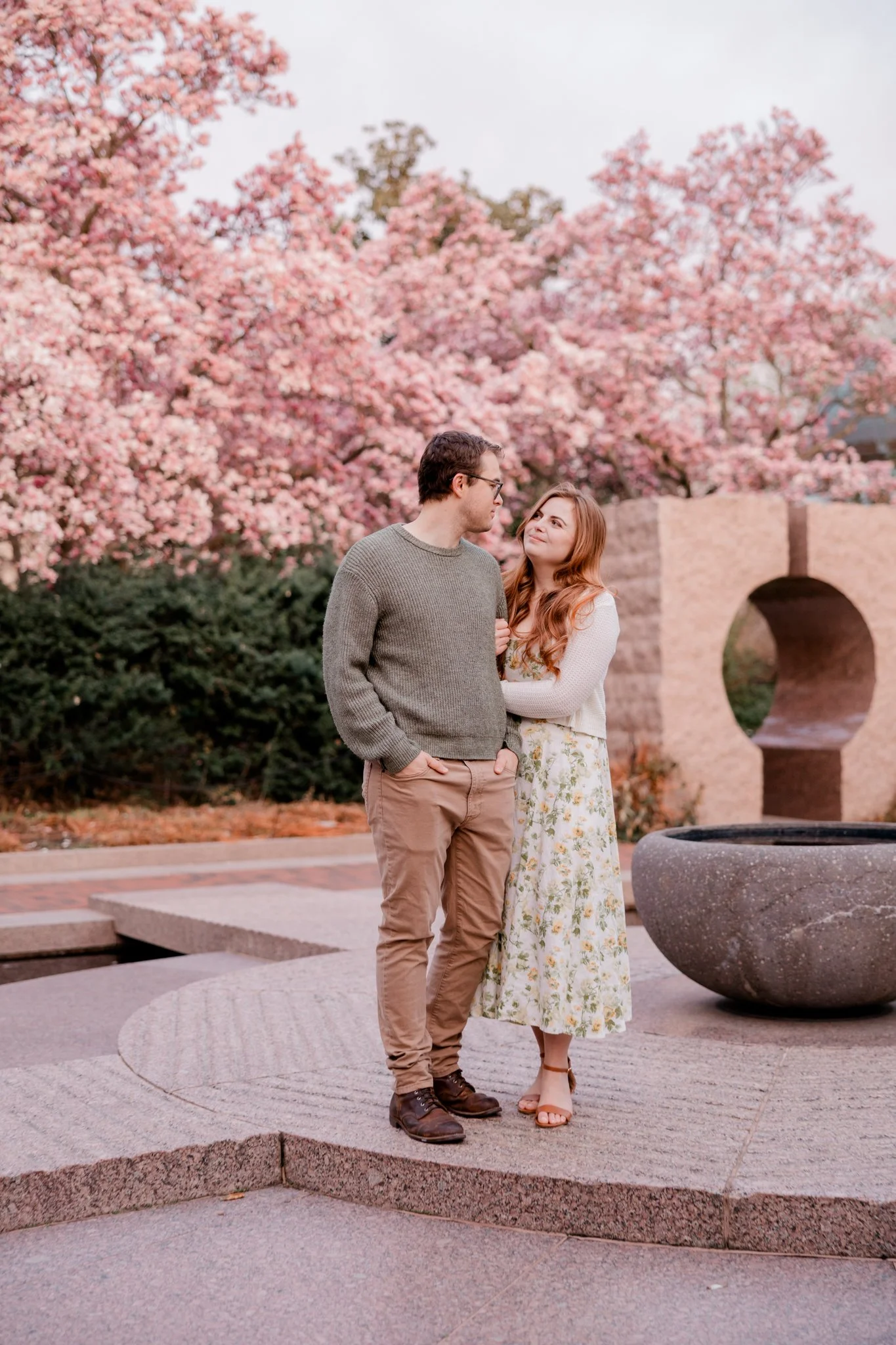 Couple posing during a photo session at the Enid Haupt Garden with pink magnolias