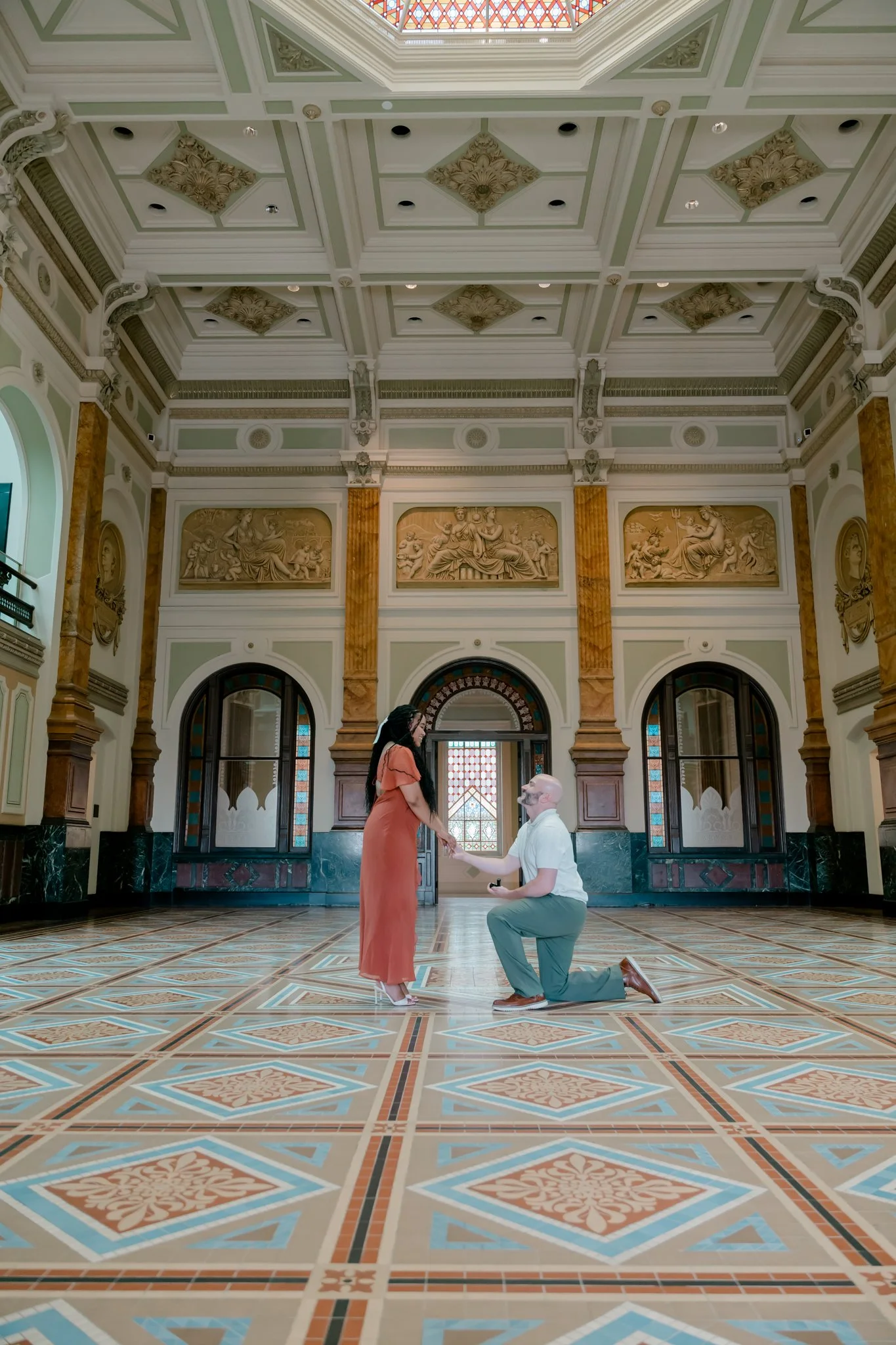 A man proposes to a woman in a spacious, ornate room in the National Portrait Gallery in Washington DC.