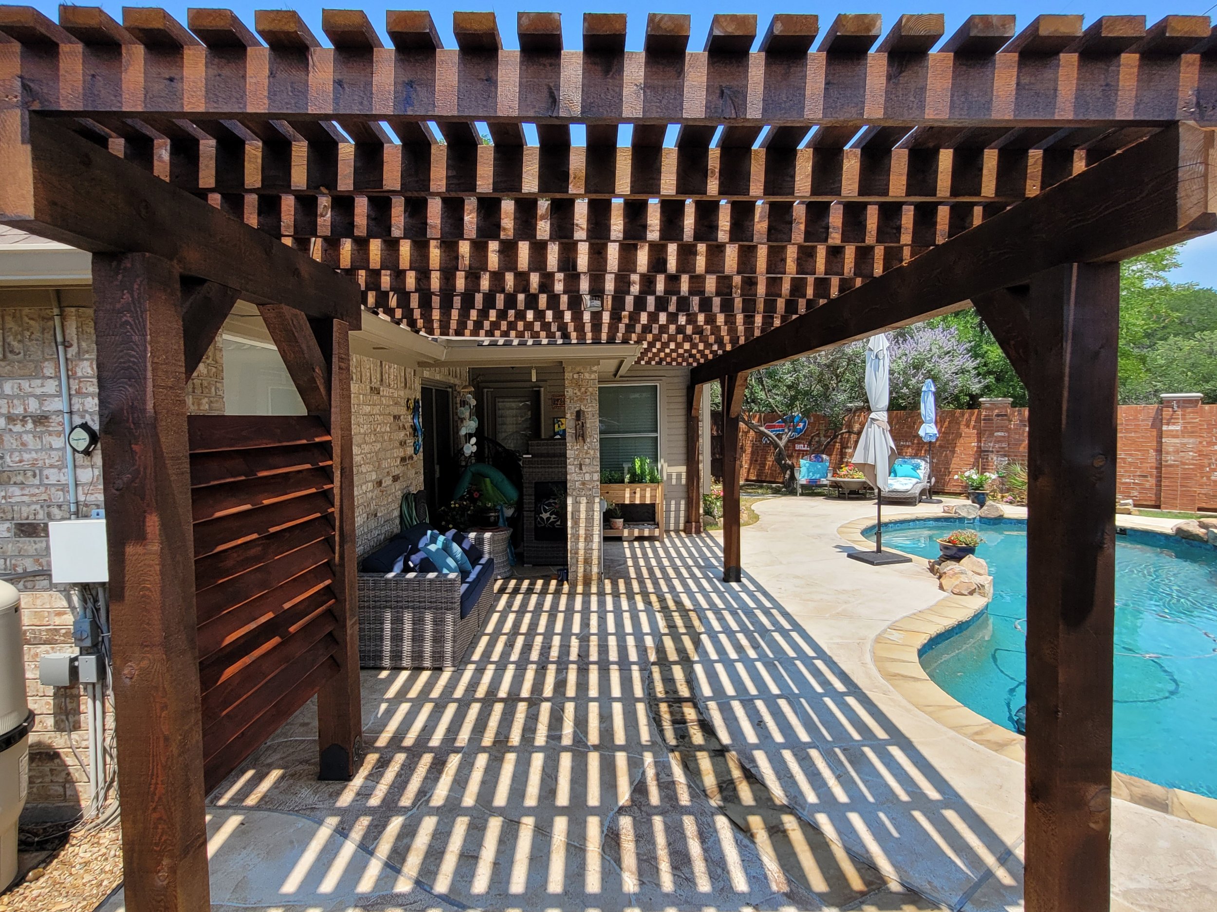 Backyard pool area with a custom wooden pergola