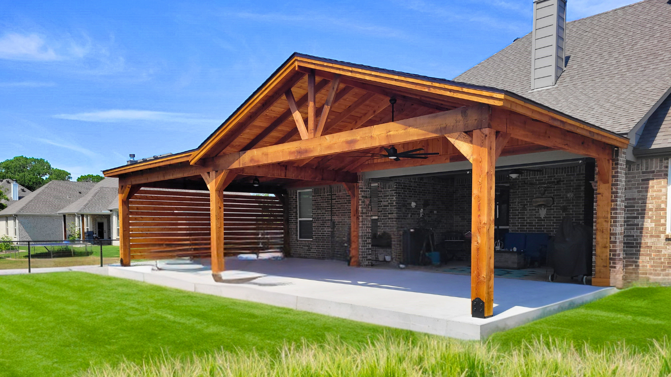 Brown wooden covered patio with ceiling fan and outdoor furniture on a concrete slab, attached to a brick house, with green grass lawn