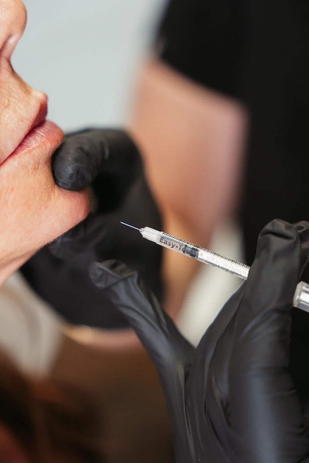 Injector treating a relaxed client, showcasing how red light therapy and botox can complement each other for enhanced anti-aging results.