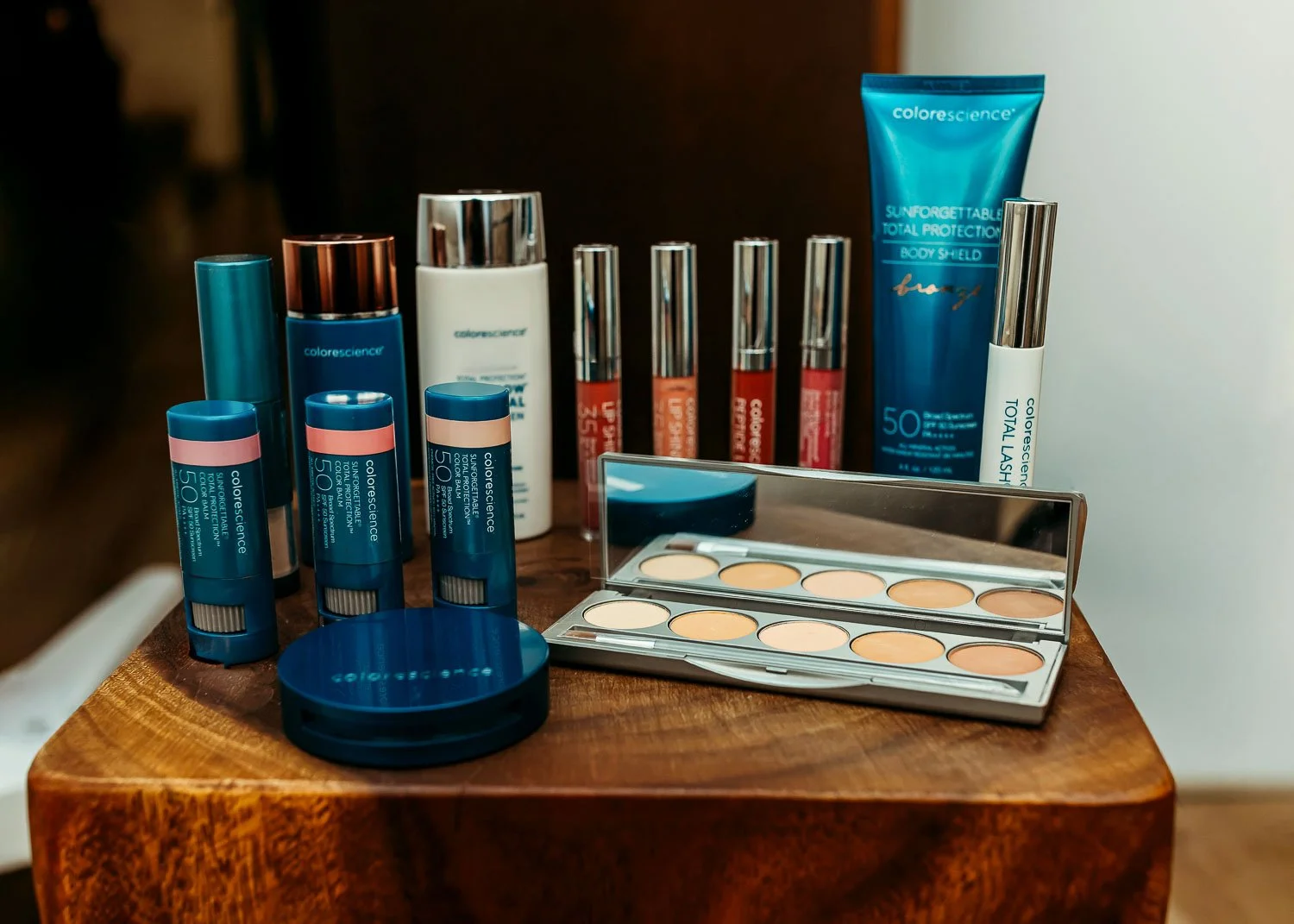 Colorscience SPF products and makeup palette displayed on a wooden surface, part of a VI peel skincare investment at INJX Bar near Peoria AZ.
