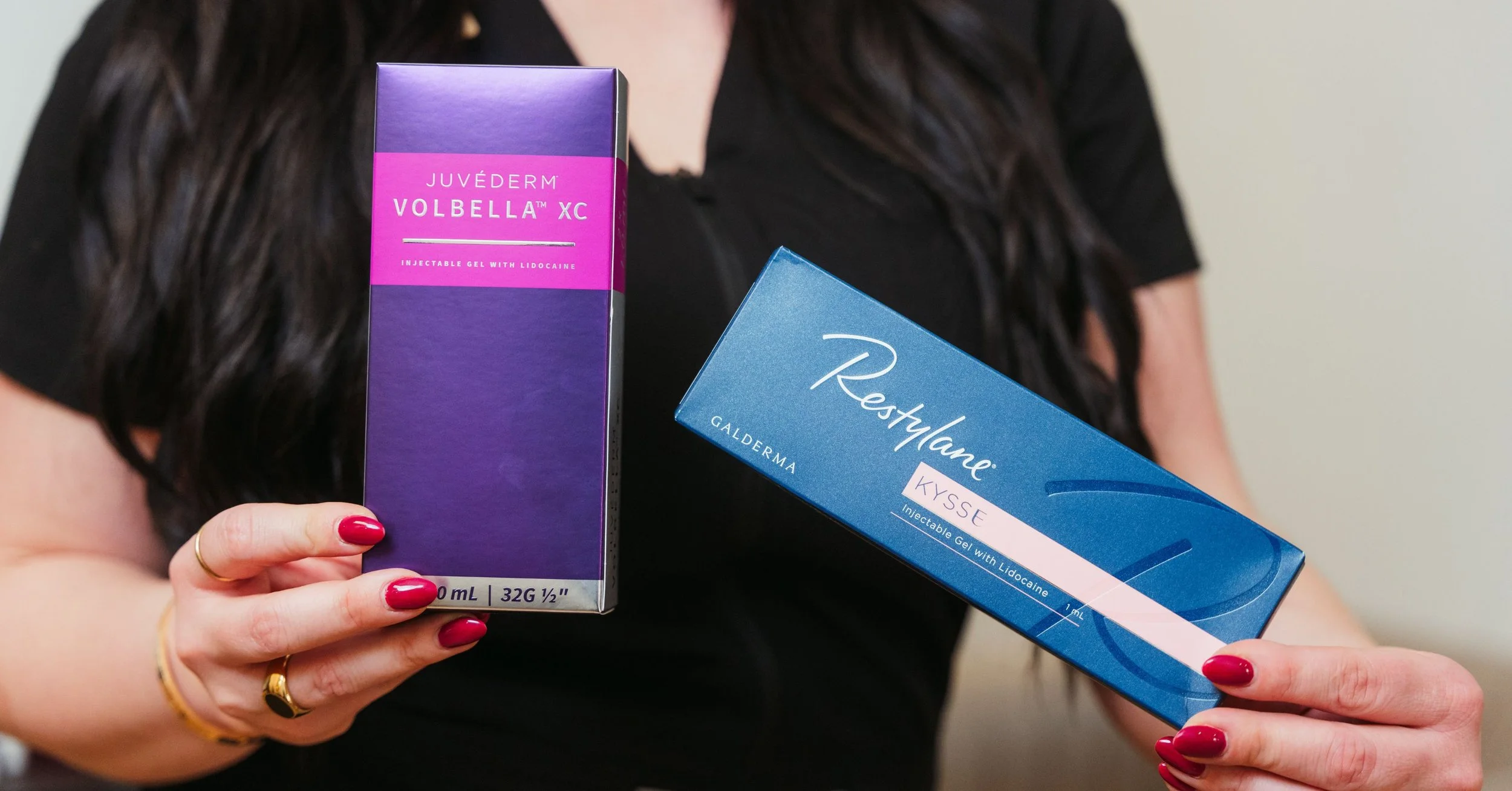Aesthetic provider holding Juvéderm Volbella and Restylane Kysse lip filler syringes at Injx Bar.
