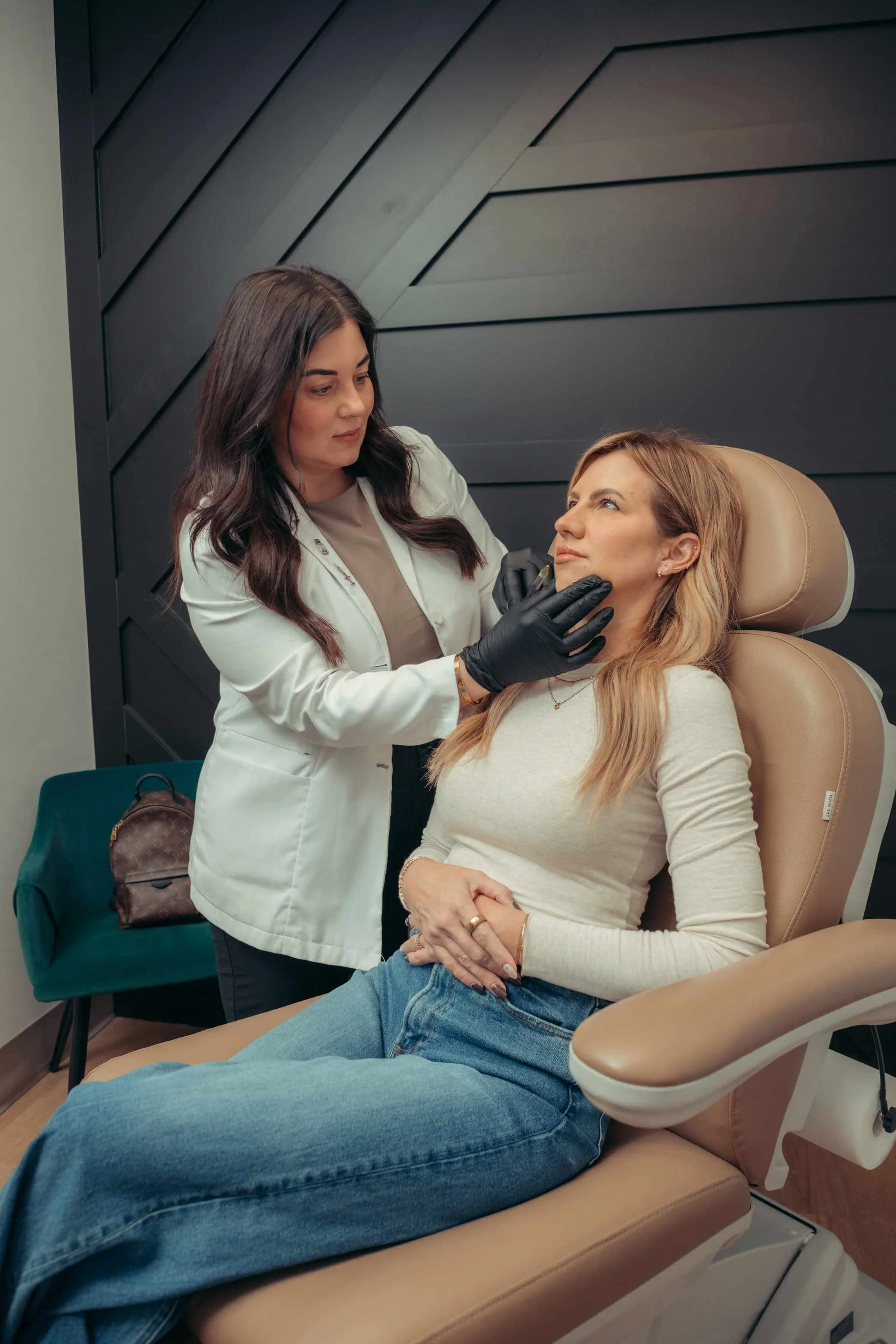 Injector consulting with a seated client before her lip filler appointment, a first step patients take when asking how long lip fillers last.