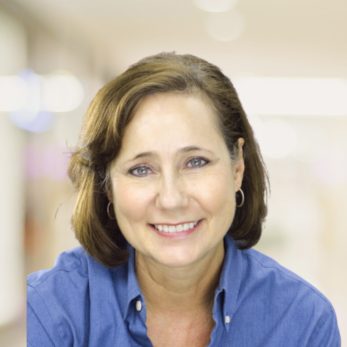 A woman wearing a blue "Power Skills" shirt, smiling with a neutral background.