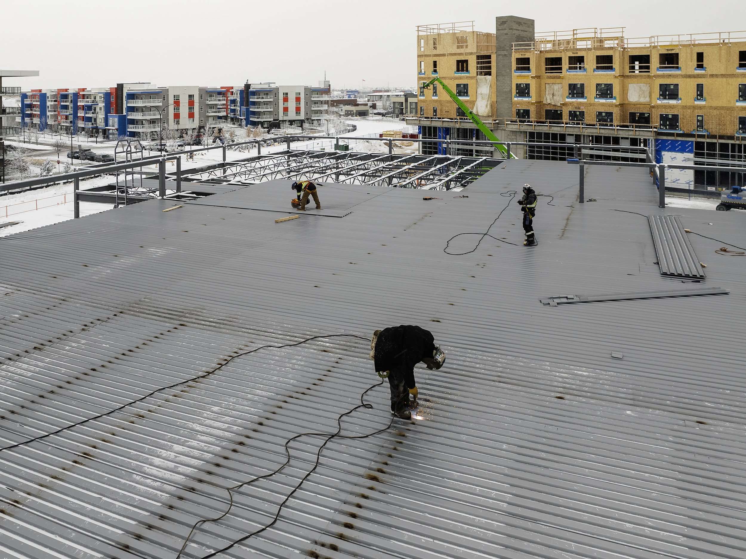  Framers on the roof working on a winter day on a  building in front of AHS South Health Campus  