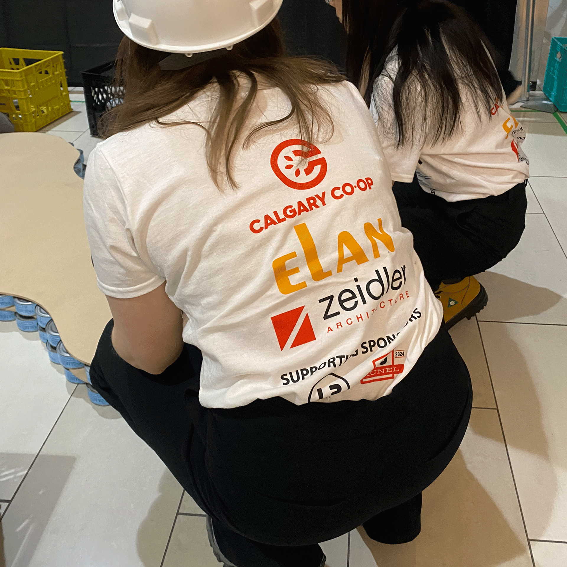 calgary-food-bank-canstruction-2025-elan-construction-women-with-sponsor-logos-on-tshirts.png