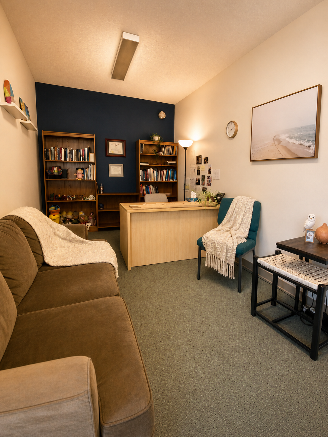 Our cozy counselling office in Cloverdale, Surrey, featuring a couch, chair and desk, and shelves with play therapy toys and books.