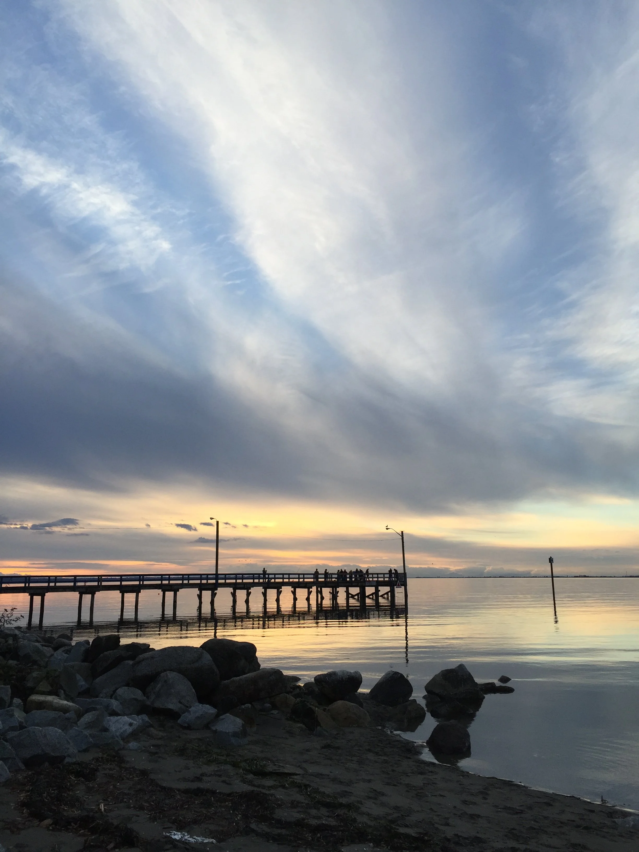 The silhouette of the board walk pier at Crescent beach in Surrey, BC at sunset. The image offers a feeling of warmth and hope even in the midst of loneliness and struggles.