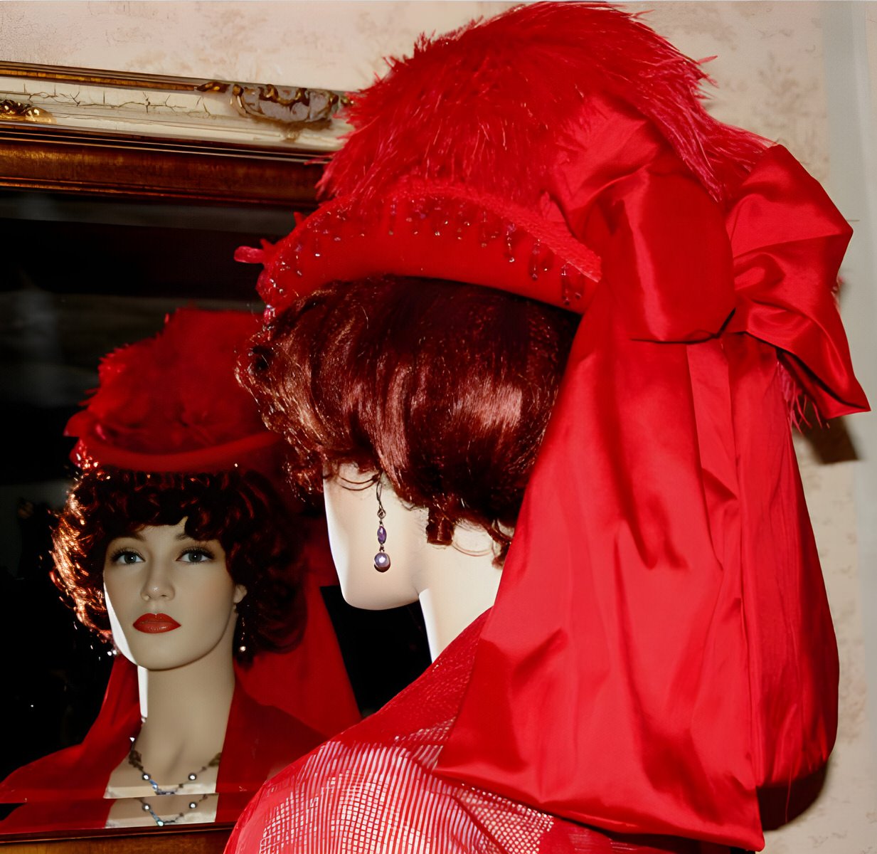 A red Victorian-style hat exuding sophistication, complemented by ostrich feathers, French beaded trim, silk bow, and floral accents.
