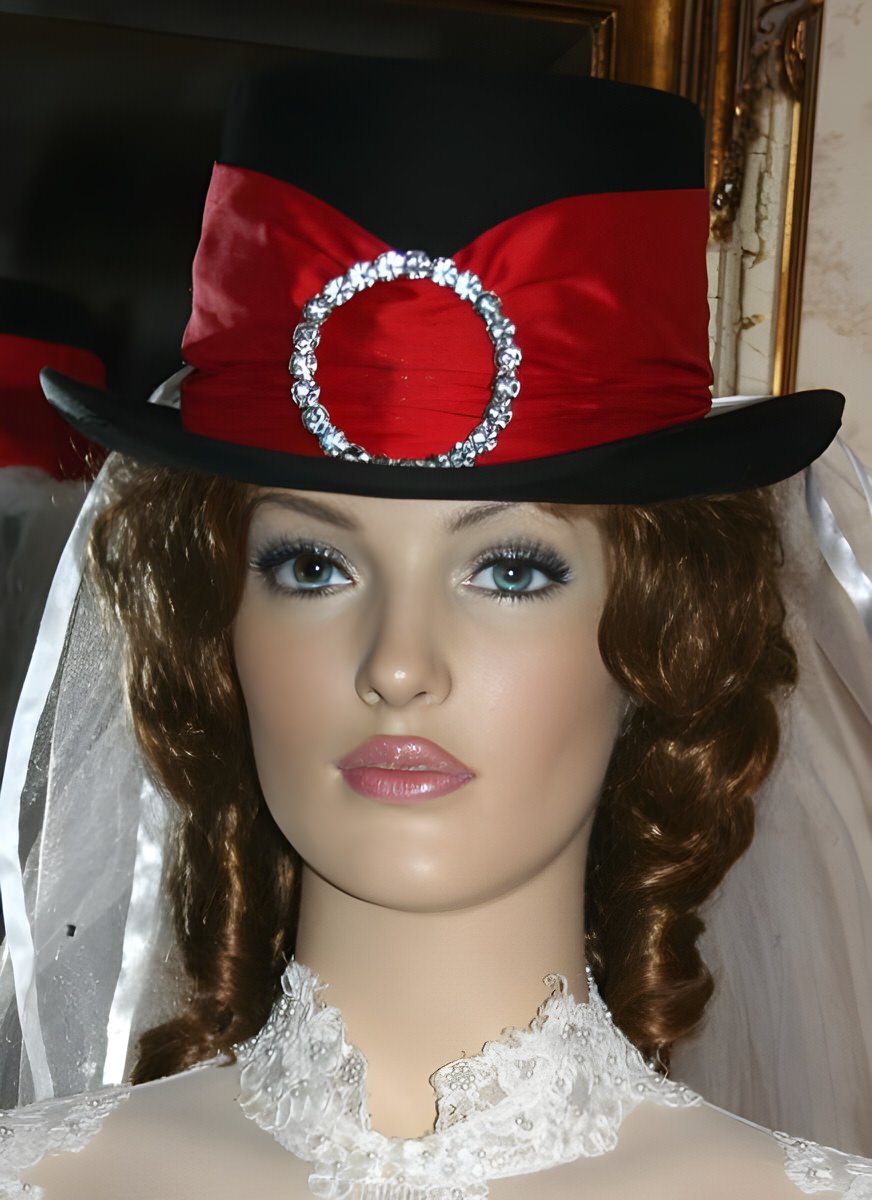 A classic black top hat with a touch of flair – adorned with a red silk band and a striking rhinestone buckle.