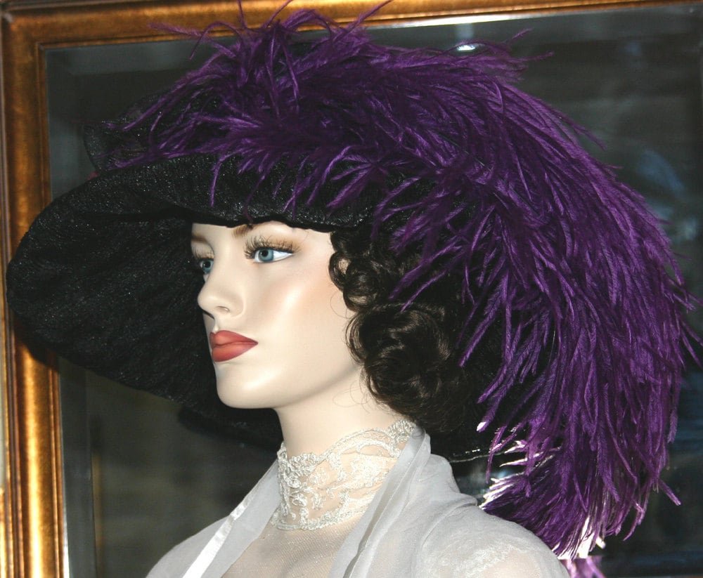 Sideview of black organza hat adorned with eggplant Ostrich feather.