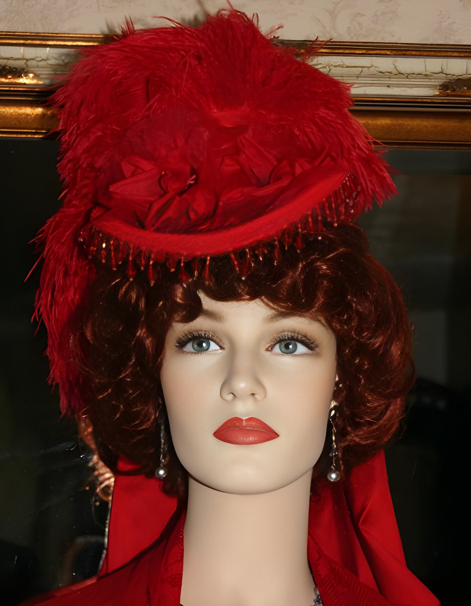 A petite, all-red Victorian Parisian-style hat with ostrich feathers, French beaded trim, silk band, bow, and charming millinery flowers.