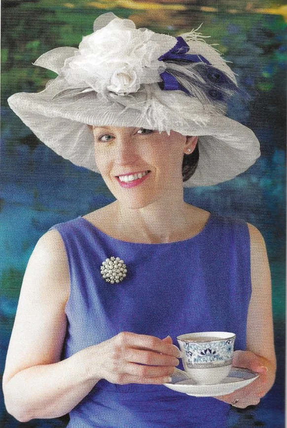 Pretty lady wearing an East Angel Harbor Hat and drinking a cup of tea.