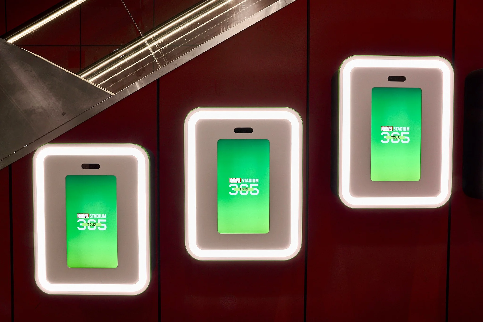 Three illuminated digital advertising displays showing a green background with the Marvel Stadium 365 Tour logo in white.