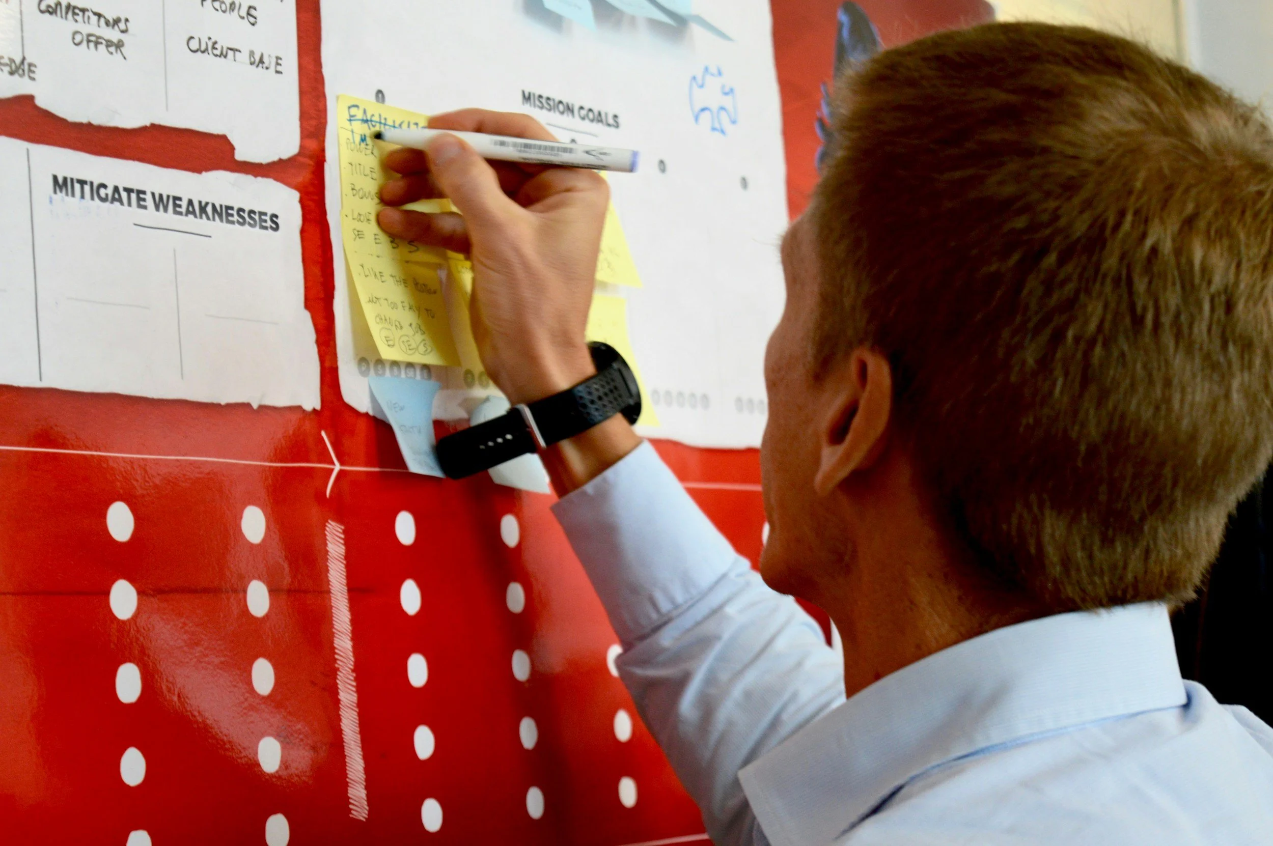 A gentleman writing notes on a sticky note on a large board