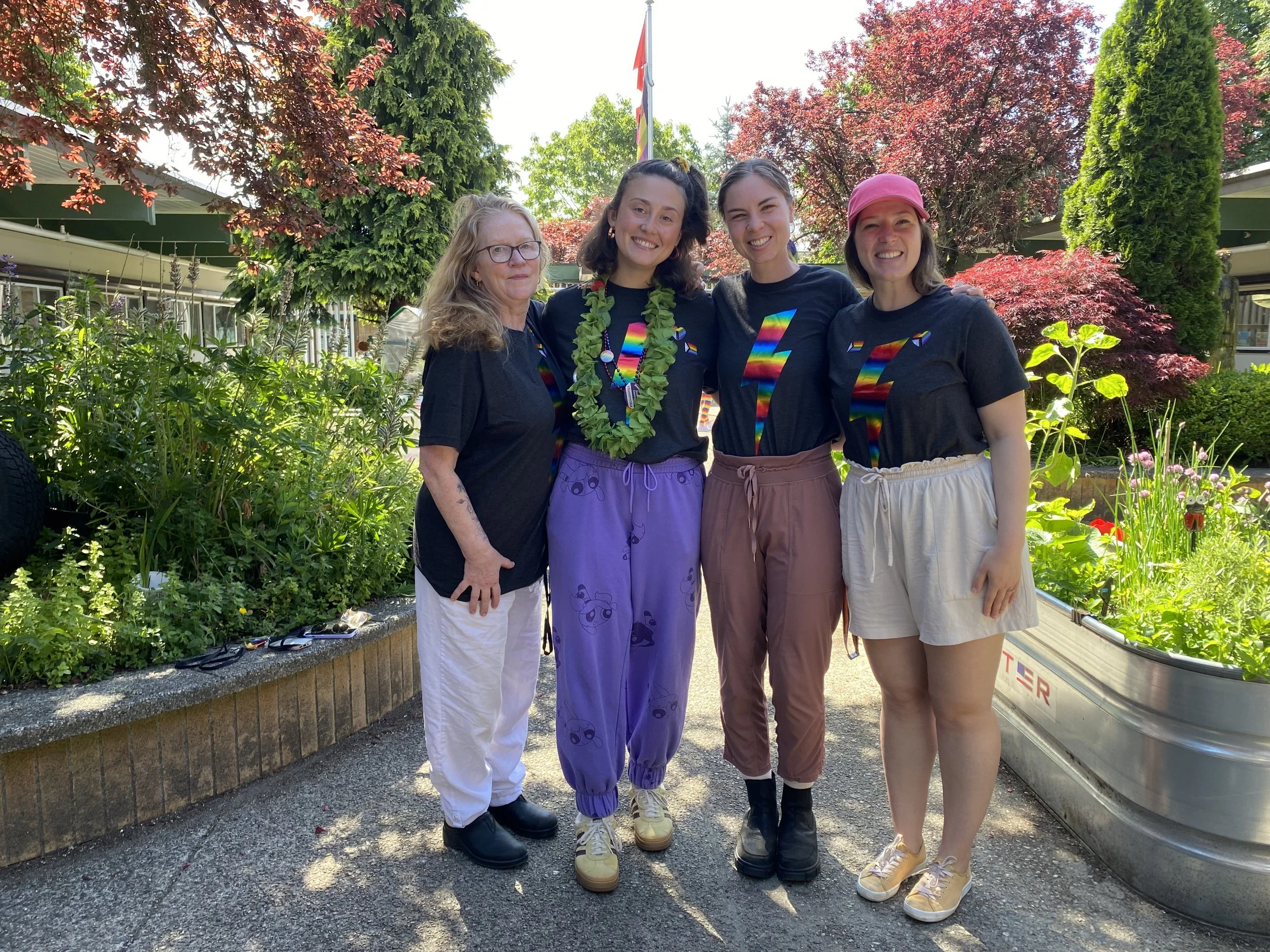 Four educators are standing together in front of a school garden courtyard.