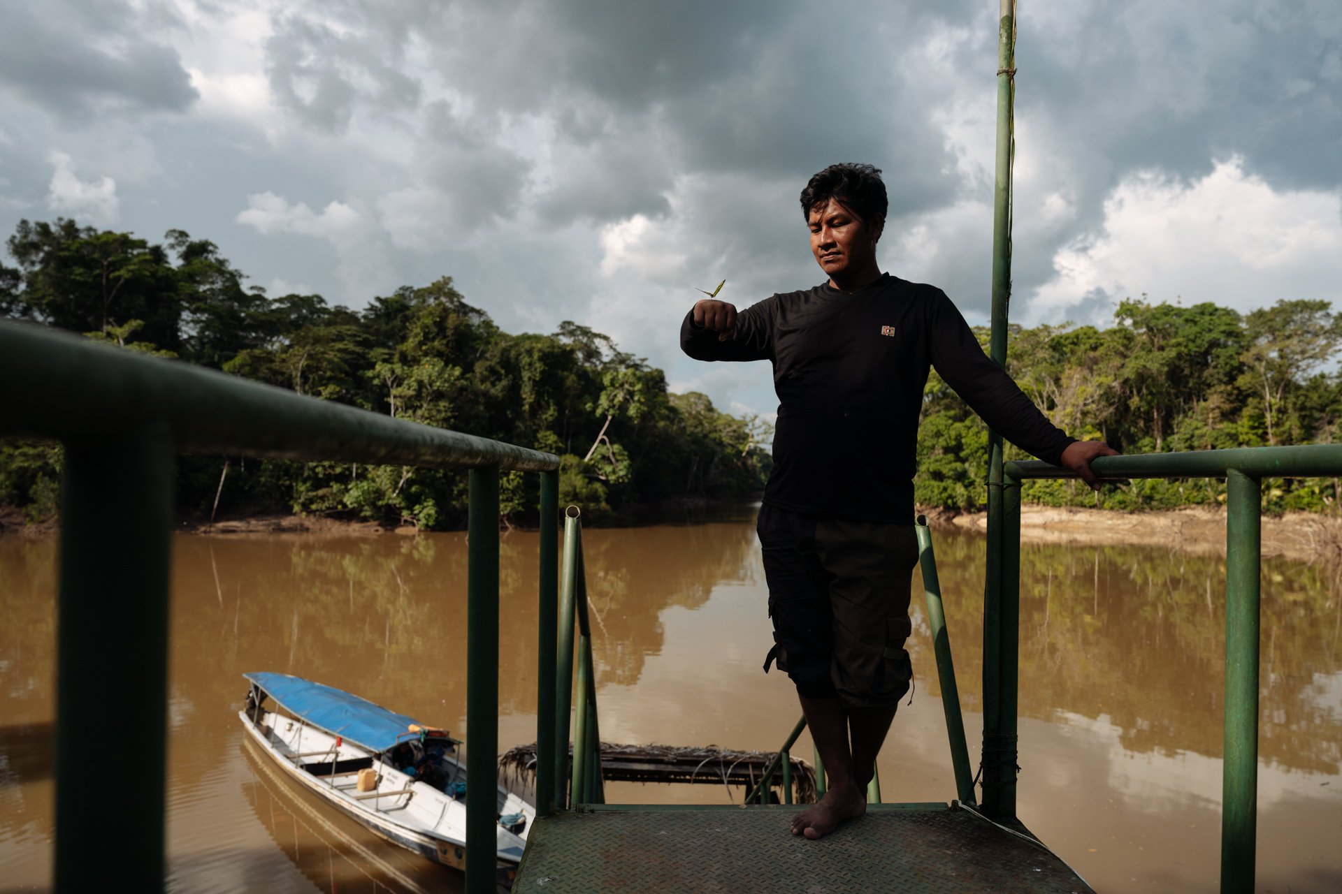 Holmer Machoa looks at a butterfly that landed on his hand at the riverside of the Tiputini River in the Yasuni national park.
