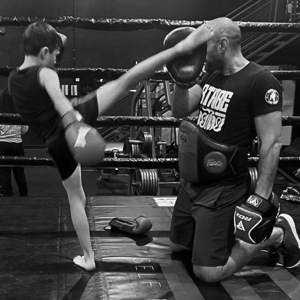 8Tribe kids Muay Thai class in San Diego—coach holding pads for kicking drills.