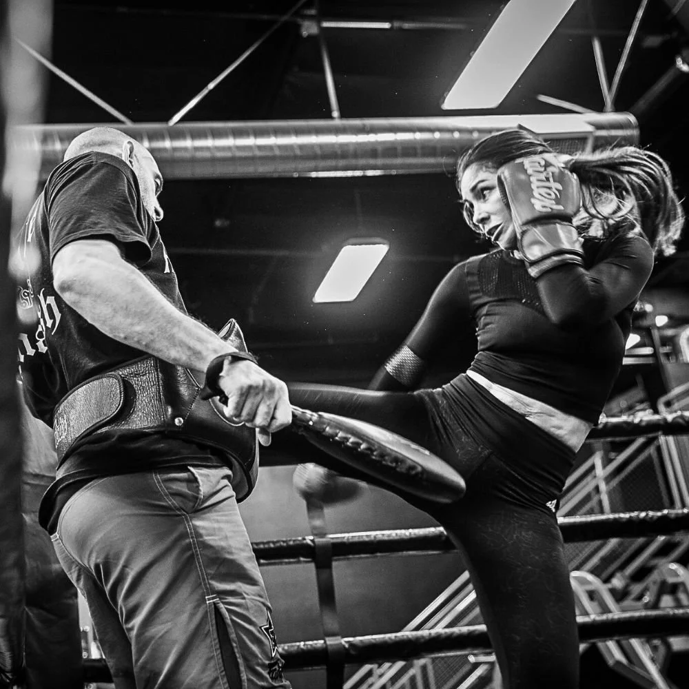 Technical Muay Thai kick training at 8Tribe San Diego—student practicing high kick on focus mitts.