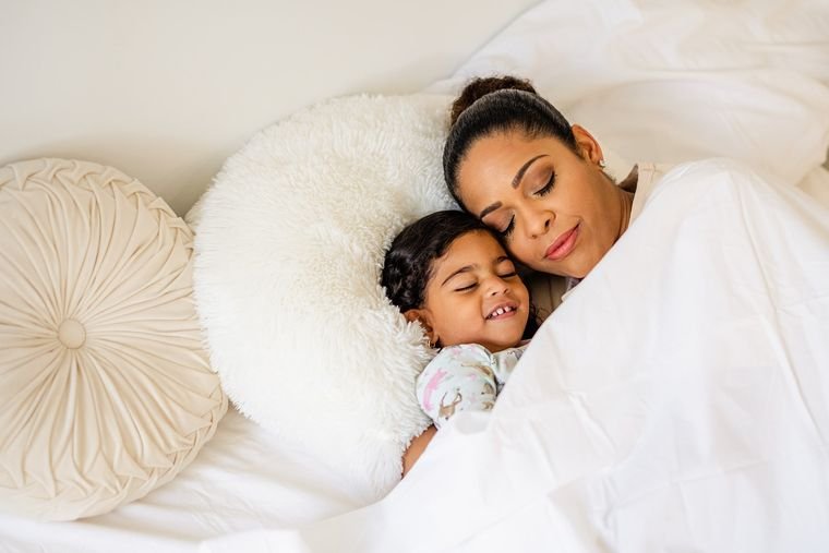 Mom and toddler resting together in bed to recover sleep after a late bedtime