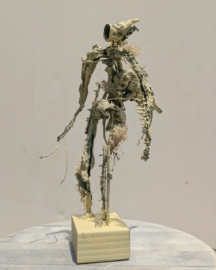 Skeletal sculpture of a humanoid figure made from bones and natural materials, mounted on a wooden base.