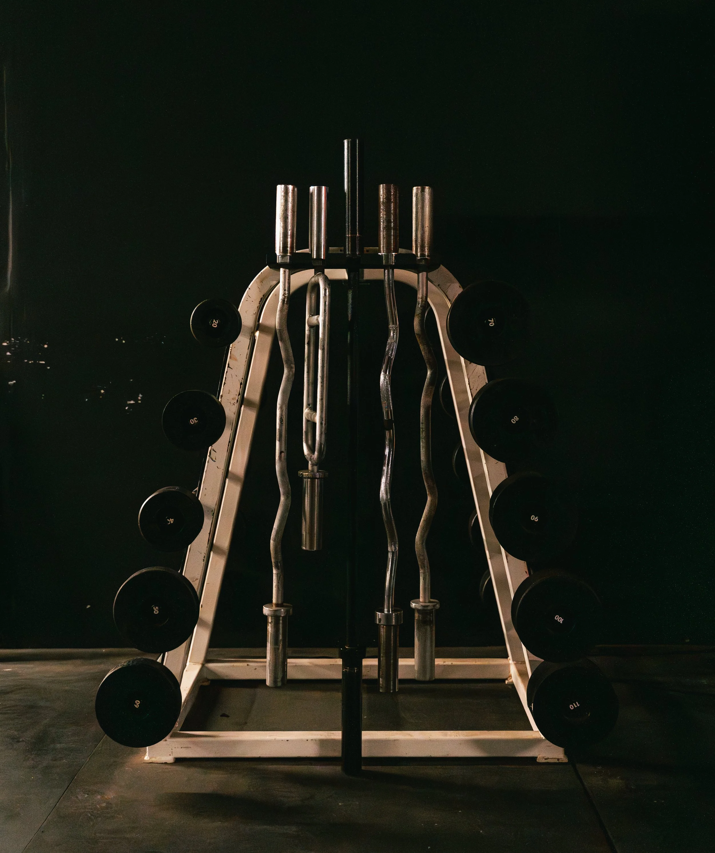Specialty barbells displayed in a vertical storage rack