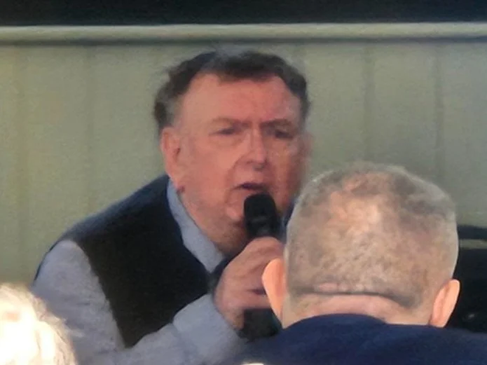 A man holding a microphone and speaking to an audience.