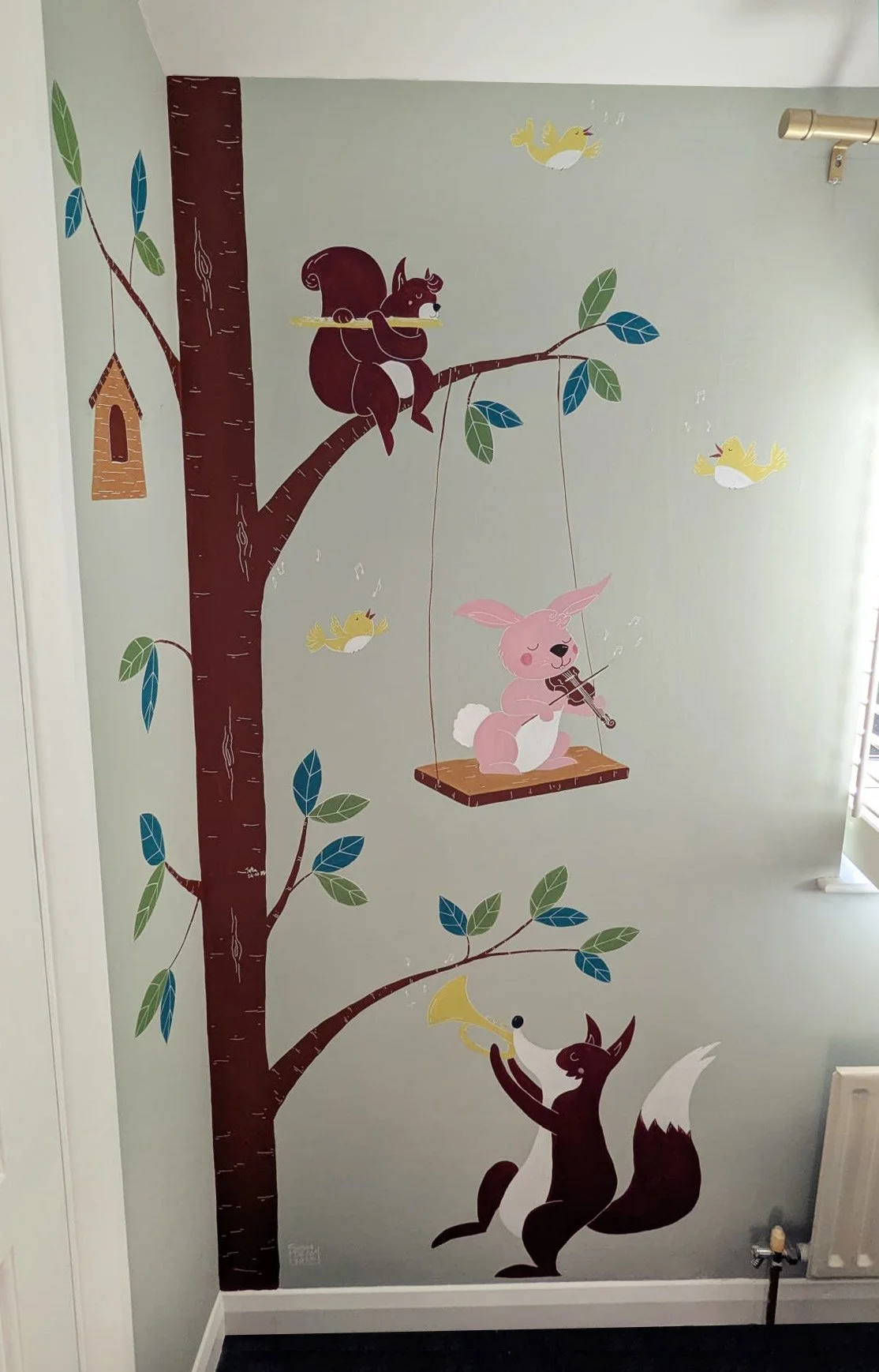 Colorful wall mural featuring a large tree with a squirrel playing a flute, a pink rabbit playing a violin on a swing, and a fox playing a trumpet, with yellow and white birds flying around.
