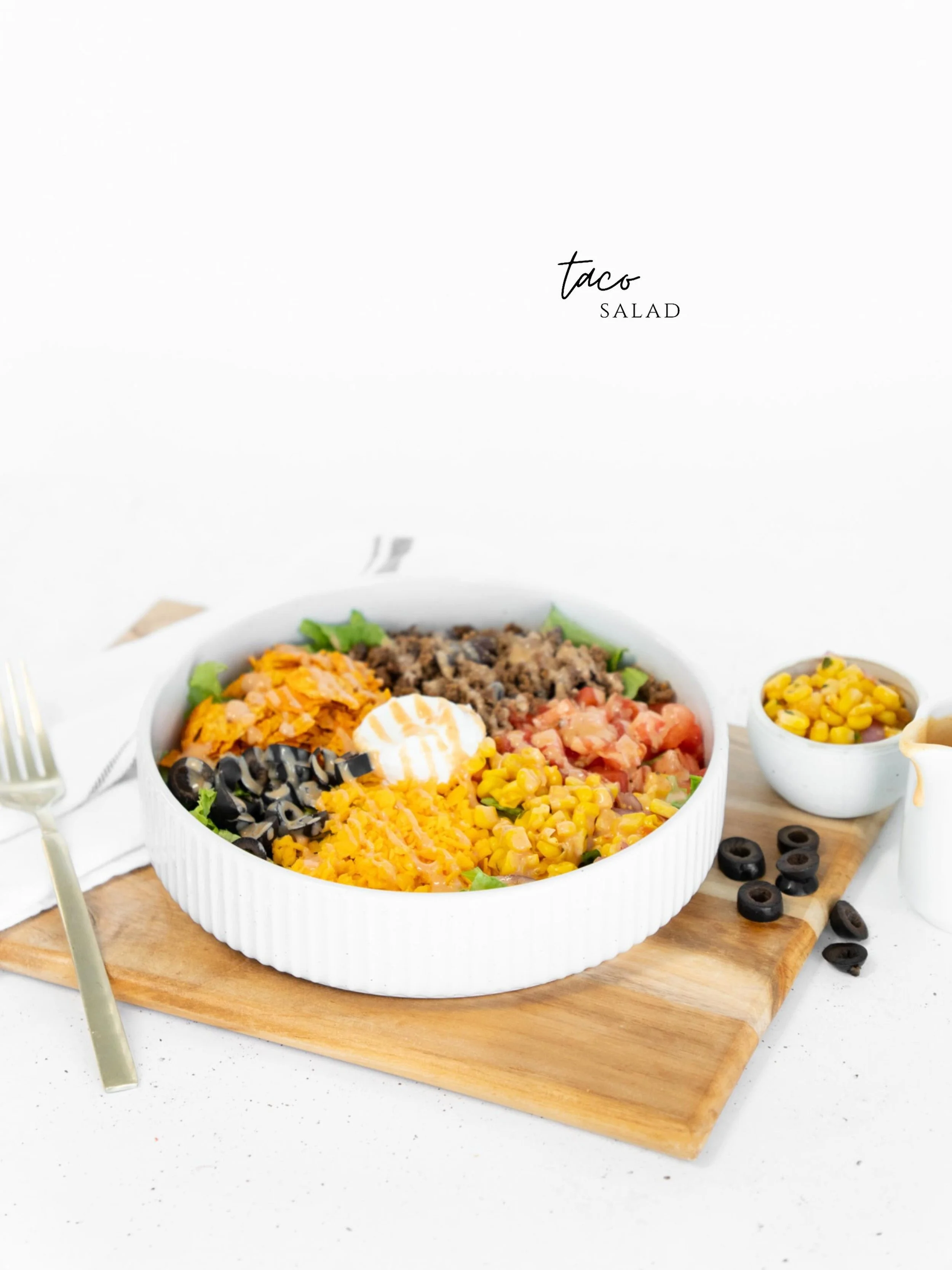 A crunchy, colorful taco salad built on a crisp bed of lettuce and loaded with seasoned taco meat, crushed Doritos, sliced olives, shredded cheese, sweet corn salsa, and juicy diced tomatoes. It&rsquo;s all finished with a cool dollop of sour cream a