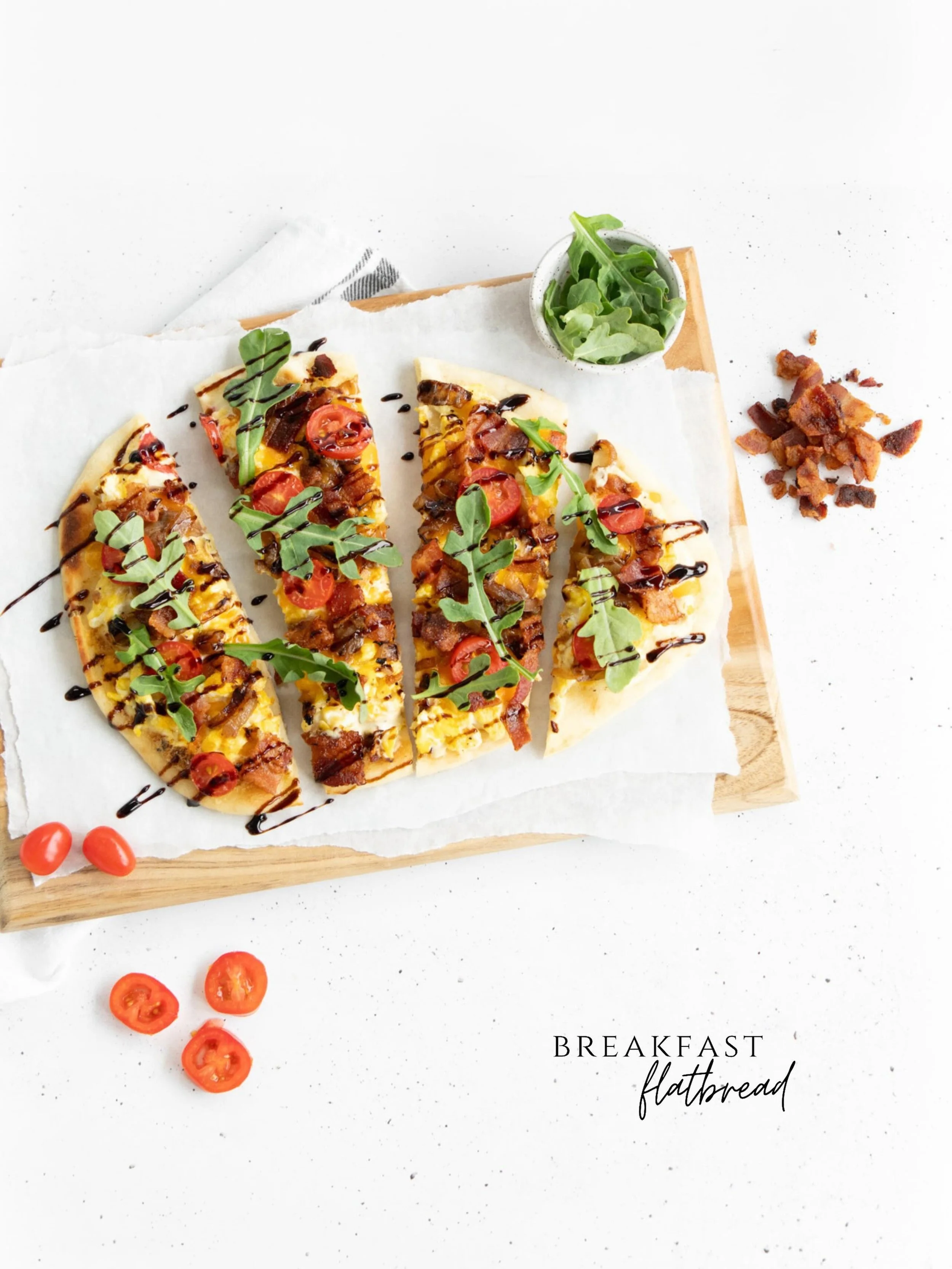Flatbread layered with creamy garlic aioli, crispy bacon, fluffy scrambled eggs, and sweet caramelized onions, then topped with fresh arugula, juicy cherry tomatoes, and a drizzle of balsamic glaze for the perfect balance of savory and fresh.