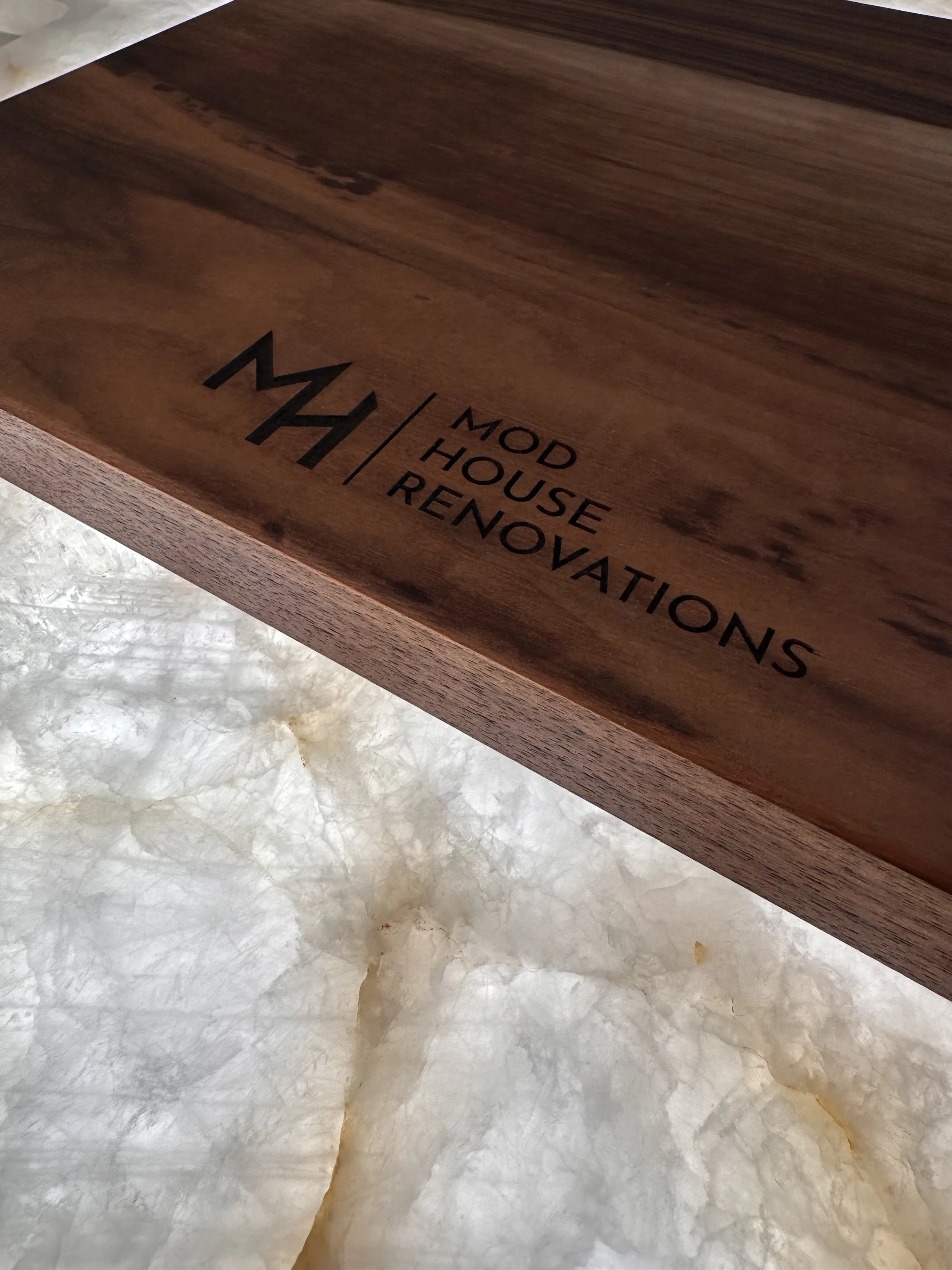 Close-up of a wooden inside of a drawer with text that reads 'MOD | HOUSE | REINVESTMENTS' printed on the bottom.