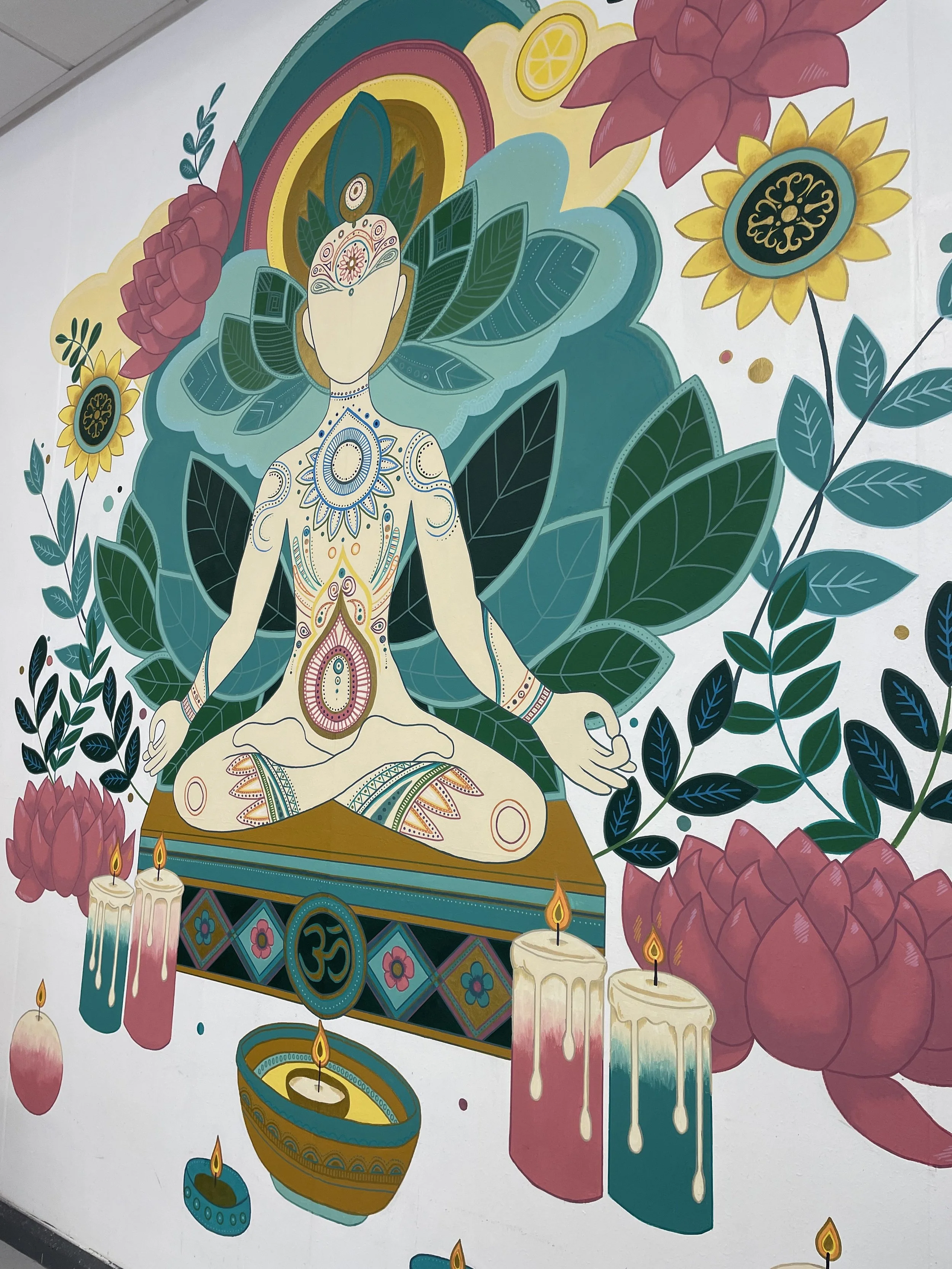 Colorful mural featuring a meditative figure with sacred symbols, surrounded by lotus flowers, candles, and vibrant leaves.