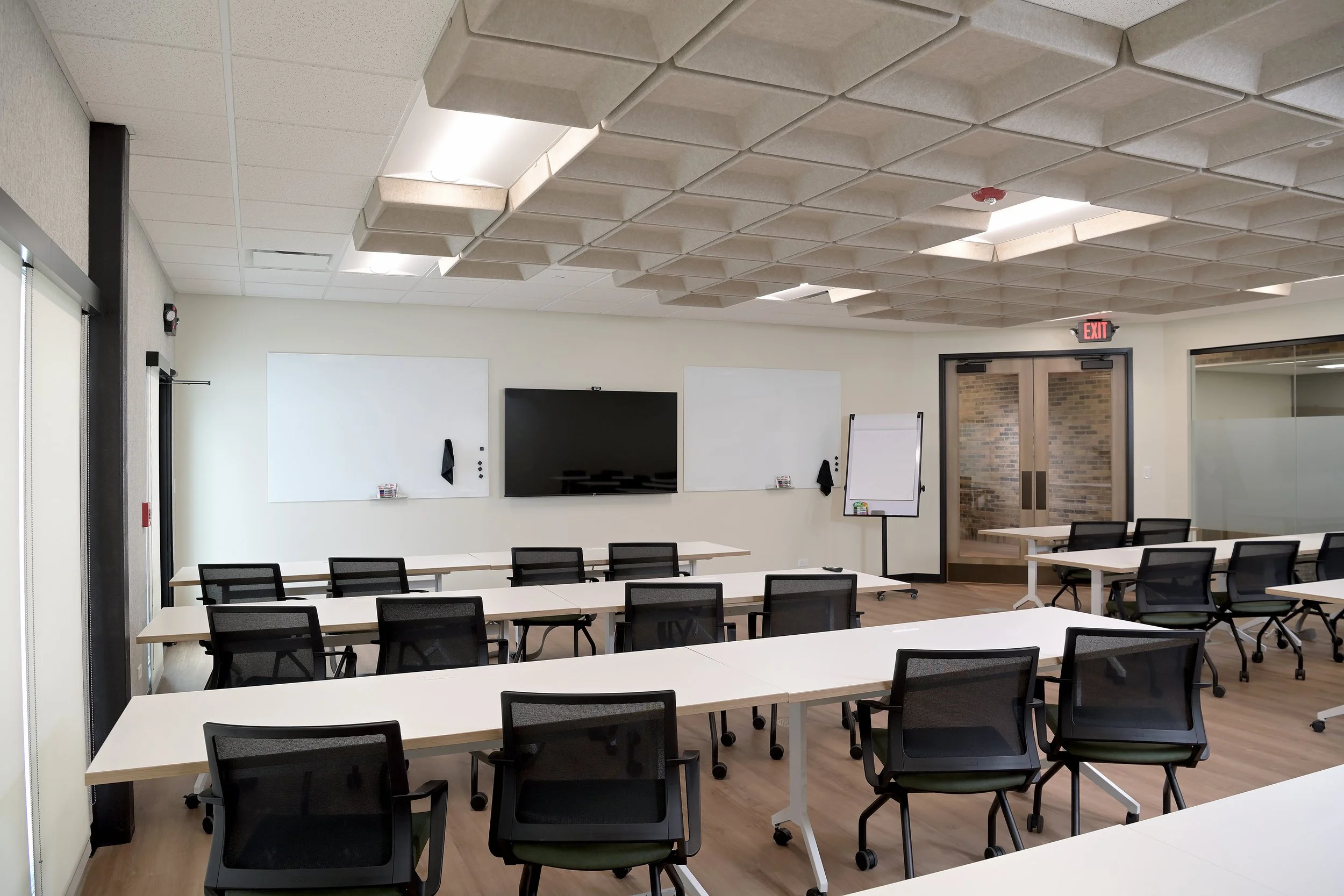 Row conference tables set up classroom style. Front of room with whiteboards and TV