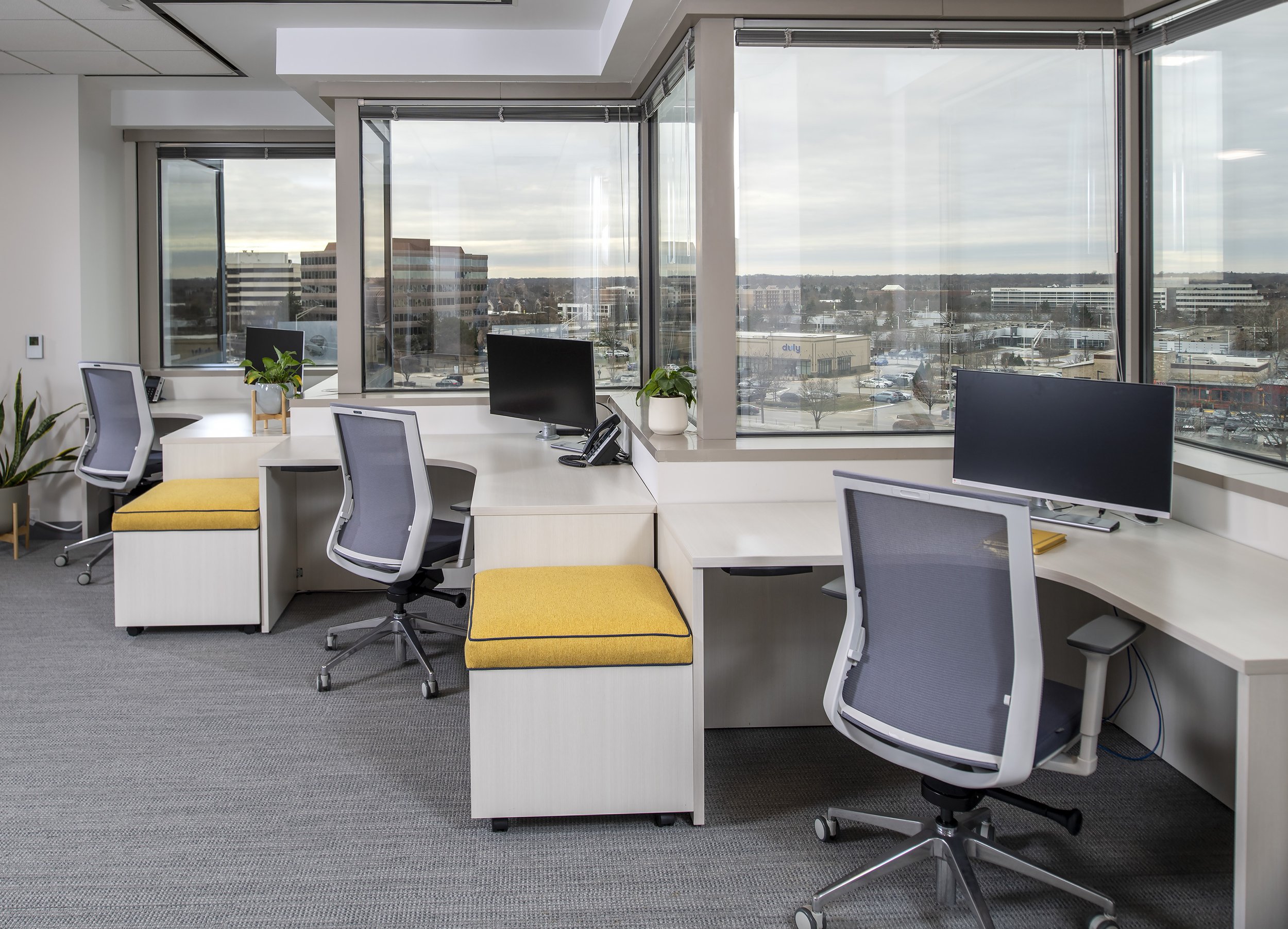 Built in workstations along corner window wall with pop of yellow benches